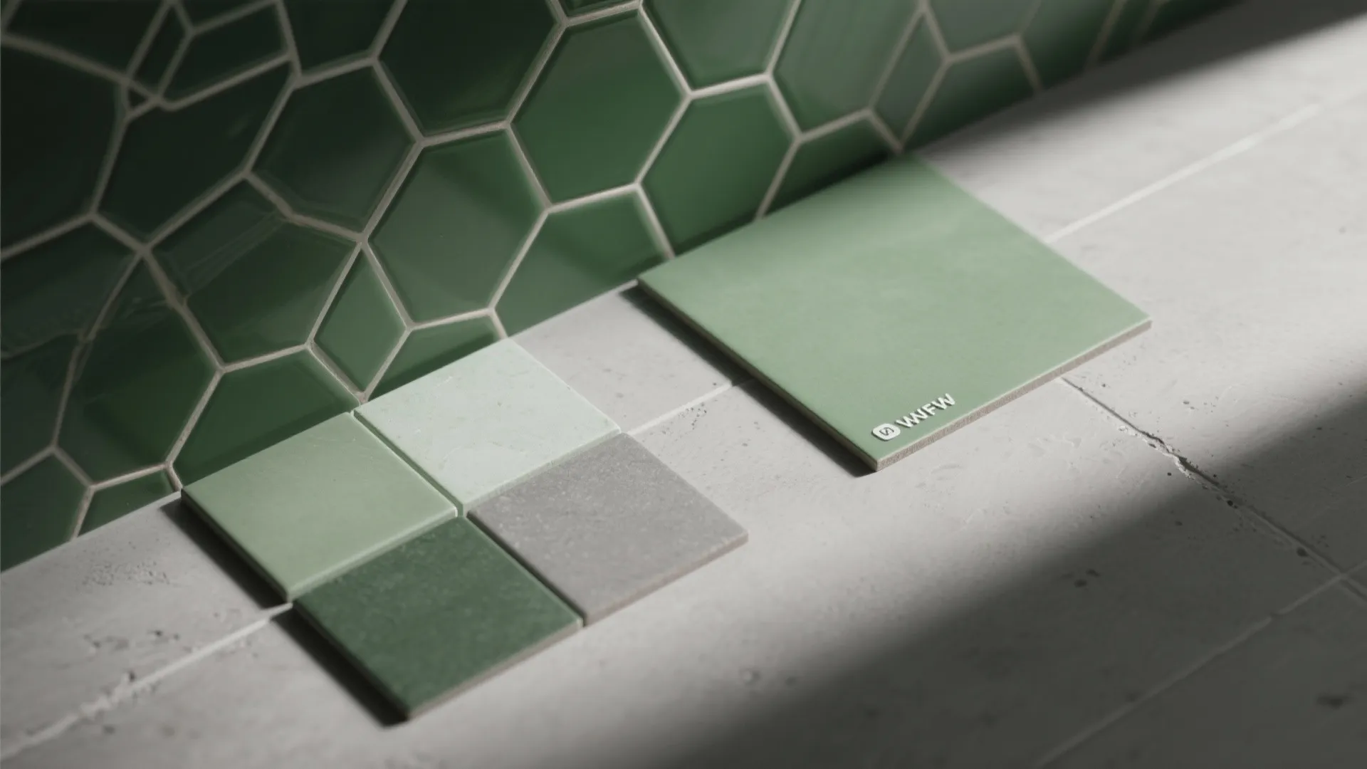 Green hexagon wall tiles next to small square green and grey floor tiles on concrete