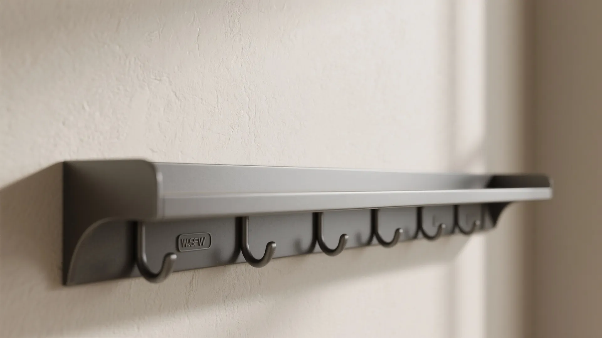 Simple grey wall mounted shelf with hooks attached to light beige colored textured indoor wall