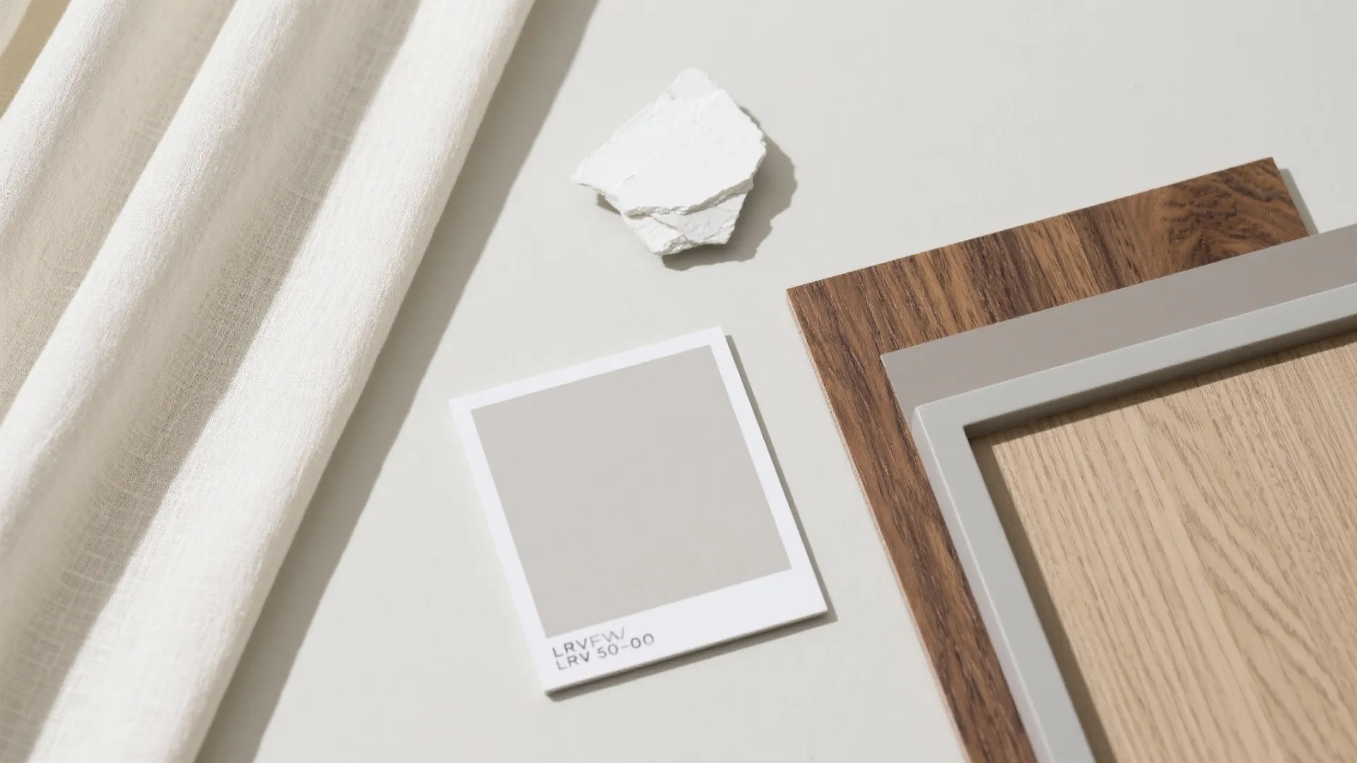 Top-down flatlay of greige paint swatches, off-white ceiling chip, pale fabric, and wood samples.