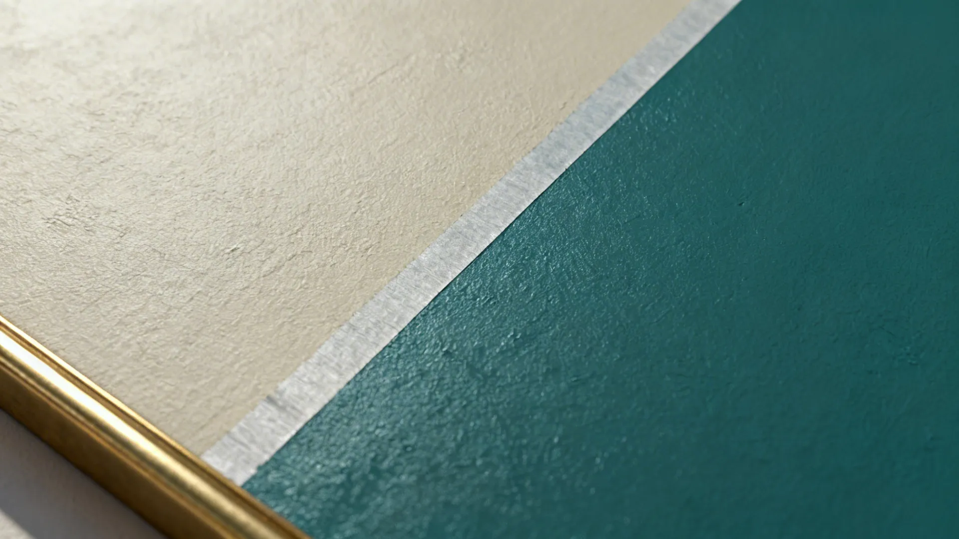 Close up of wall showing cream and teal paint separated by a thin silver tape