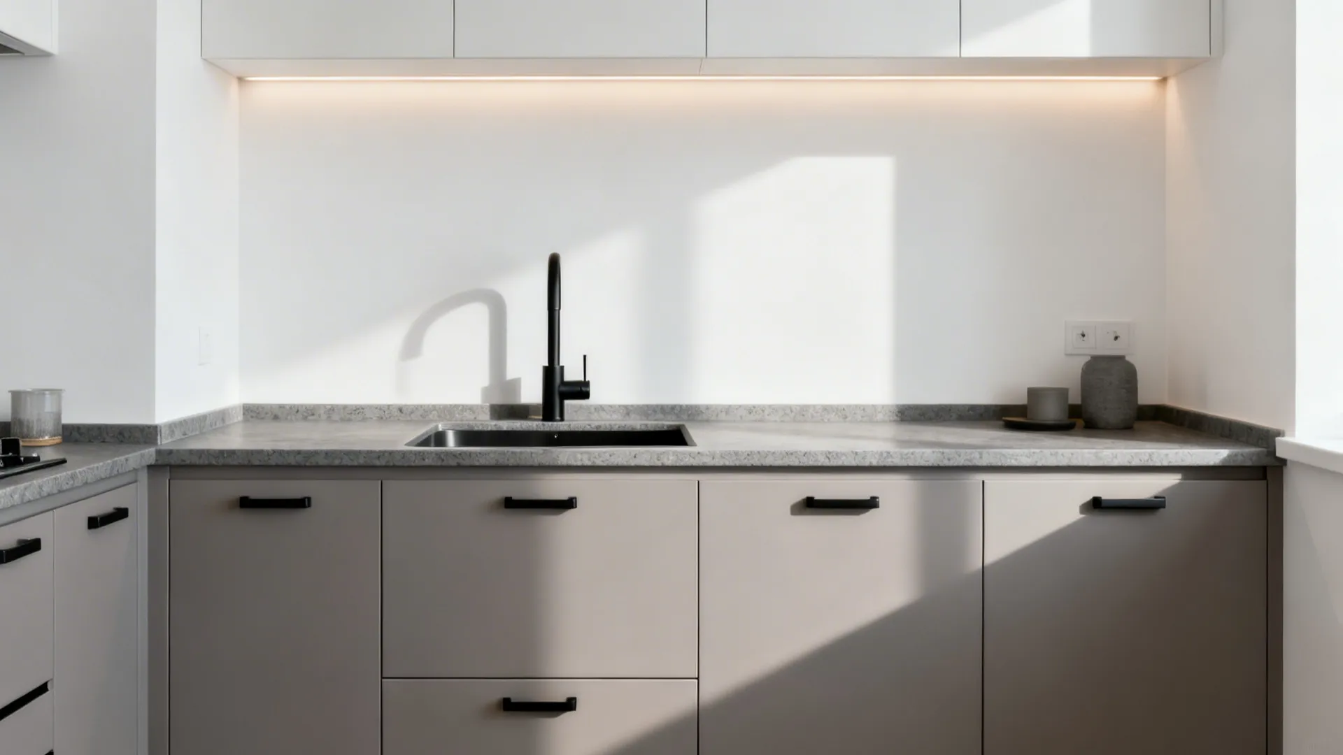 Soft grey lower cabinets with matte black pulls and faucet against bright white walls.