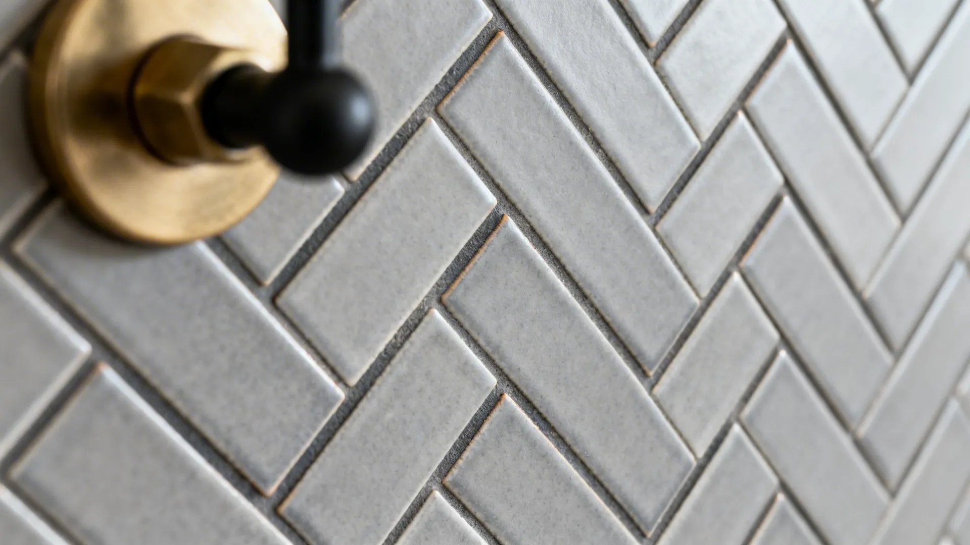 Macro of grey herringbone tiles with darker grout, showing crisp zig-zag texture and fine edges.