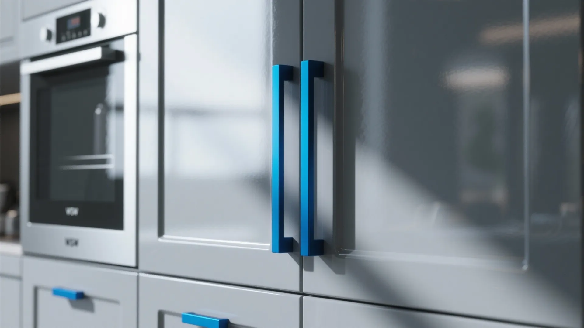 Grey kitchen cabinet doors with bright blue metal handles next to a built in oven