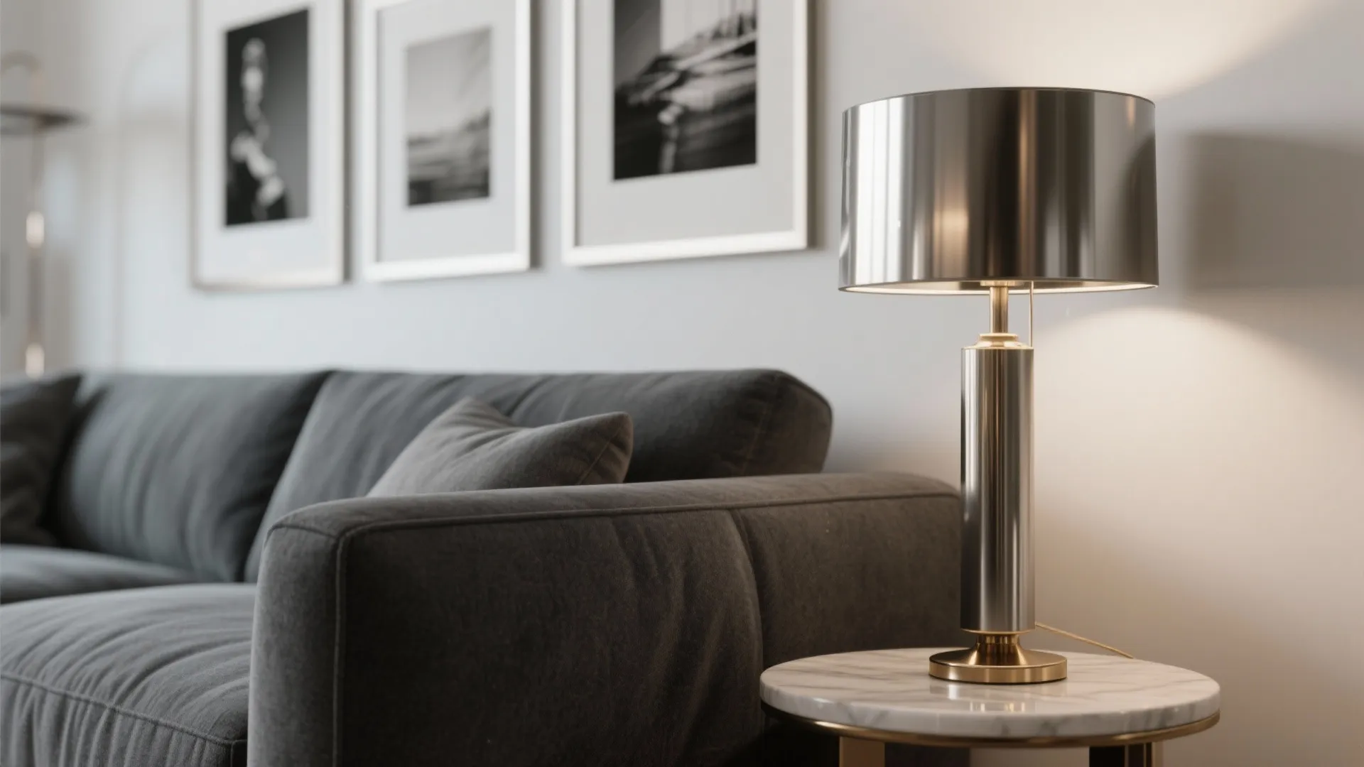 Close up of a silver table lamp on marble side table next to grey sofa