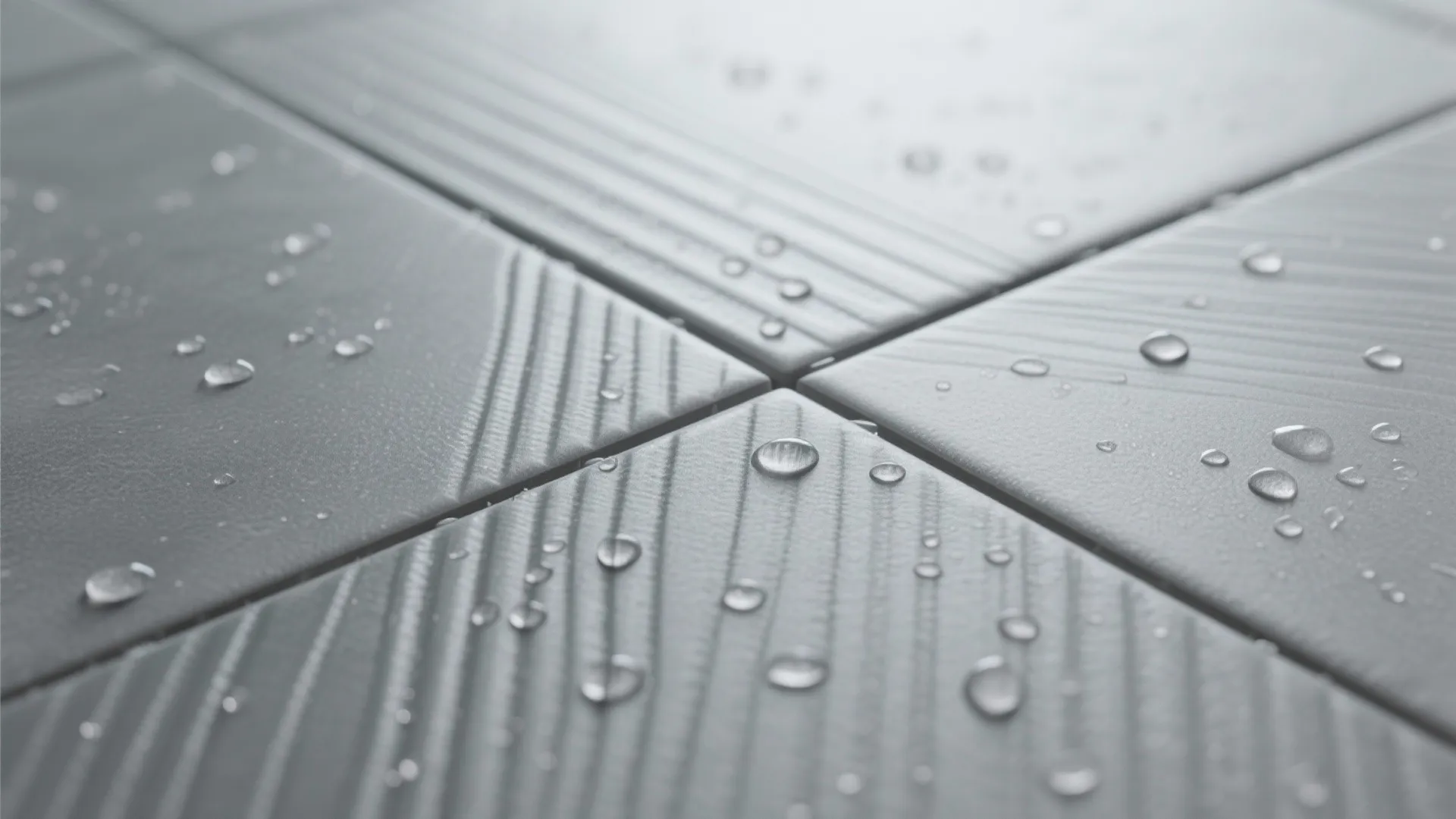 Detailed close up of gray bathroom tiles with water droplets on the textured matte surface