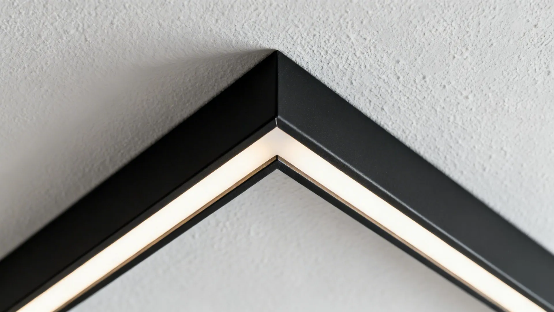 Close-up of a black metal corner frame with built-in light fixture on a white ceiling
