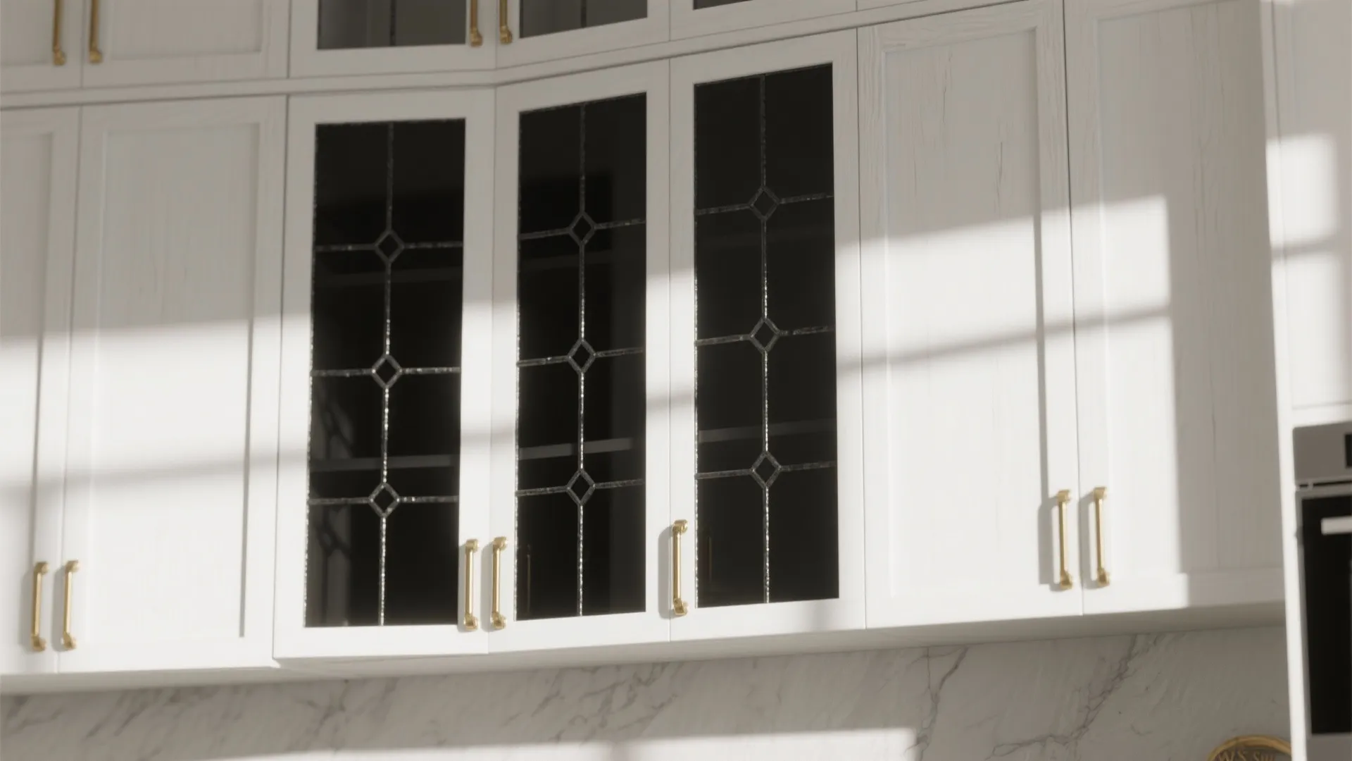 White kitchen cabinet with black gridded glass doors and gold handles under bright natural sunlight