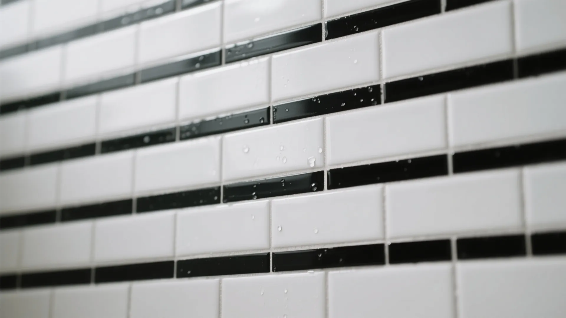 Close up view of white and black wall tiles with water drops in a modern bathroom