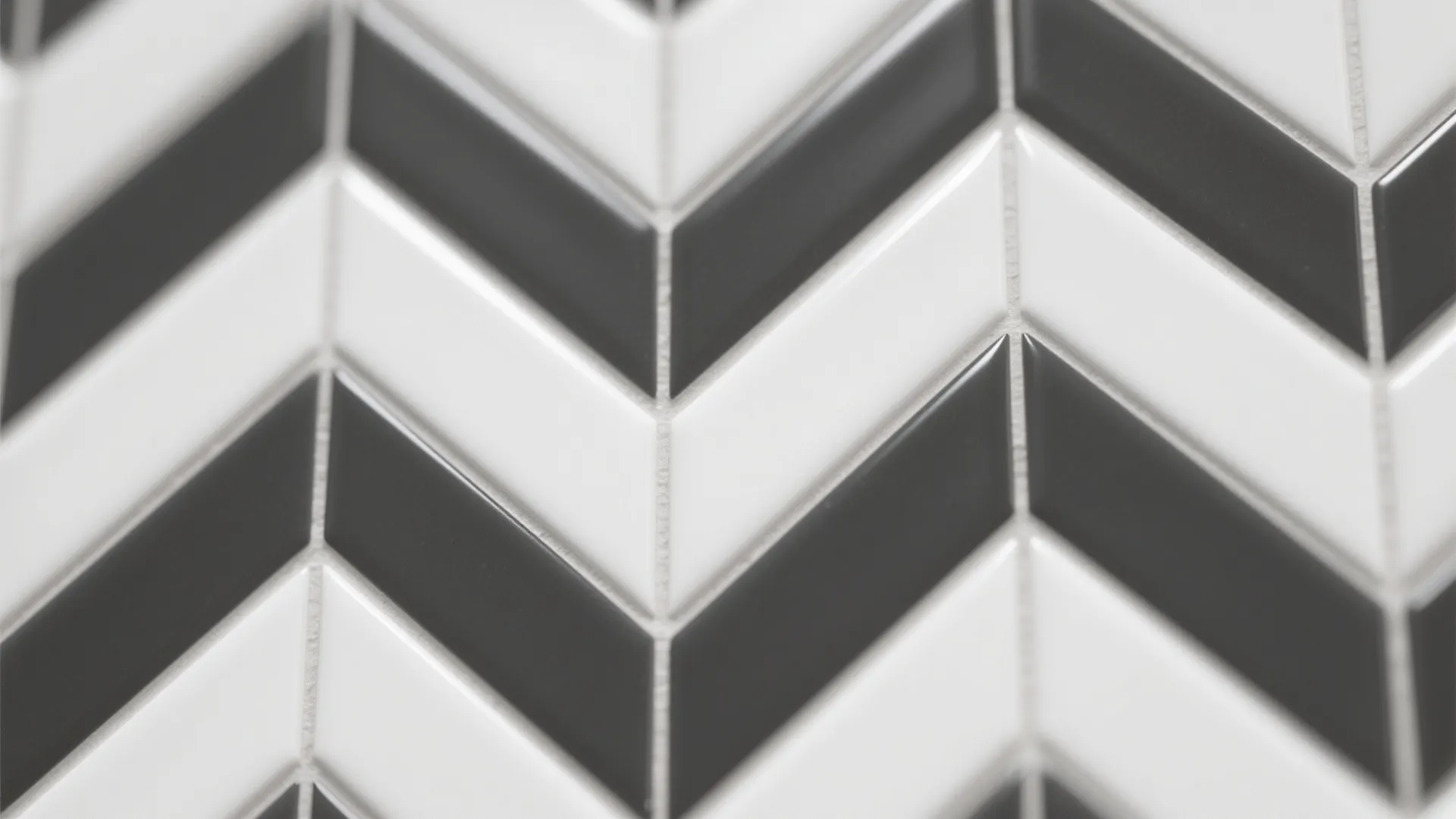 Macro of herringbone white tiles with charcoal grout outlining the pattern.