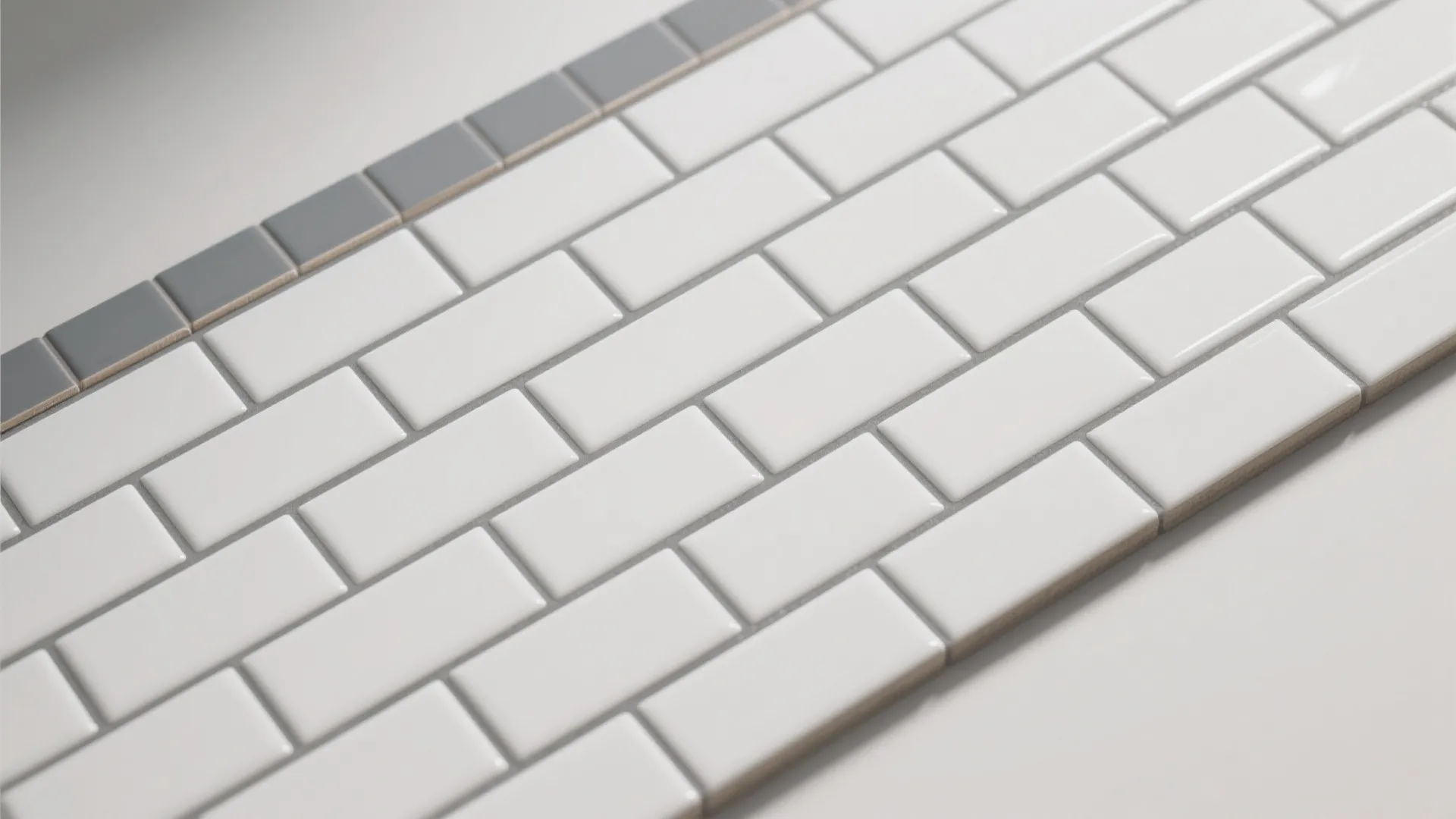 Close up view of white rectangular wall tiles with grey grout and a top border