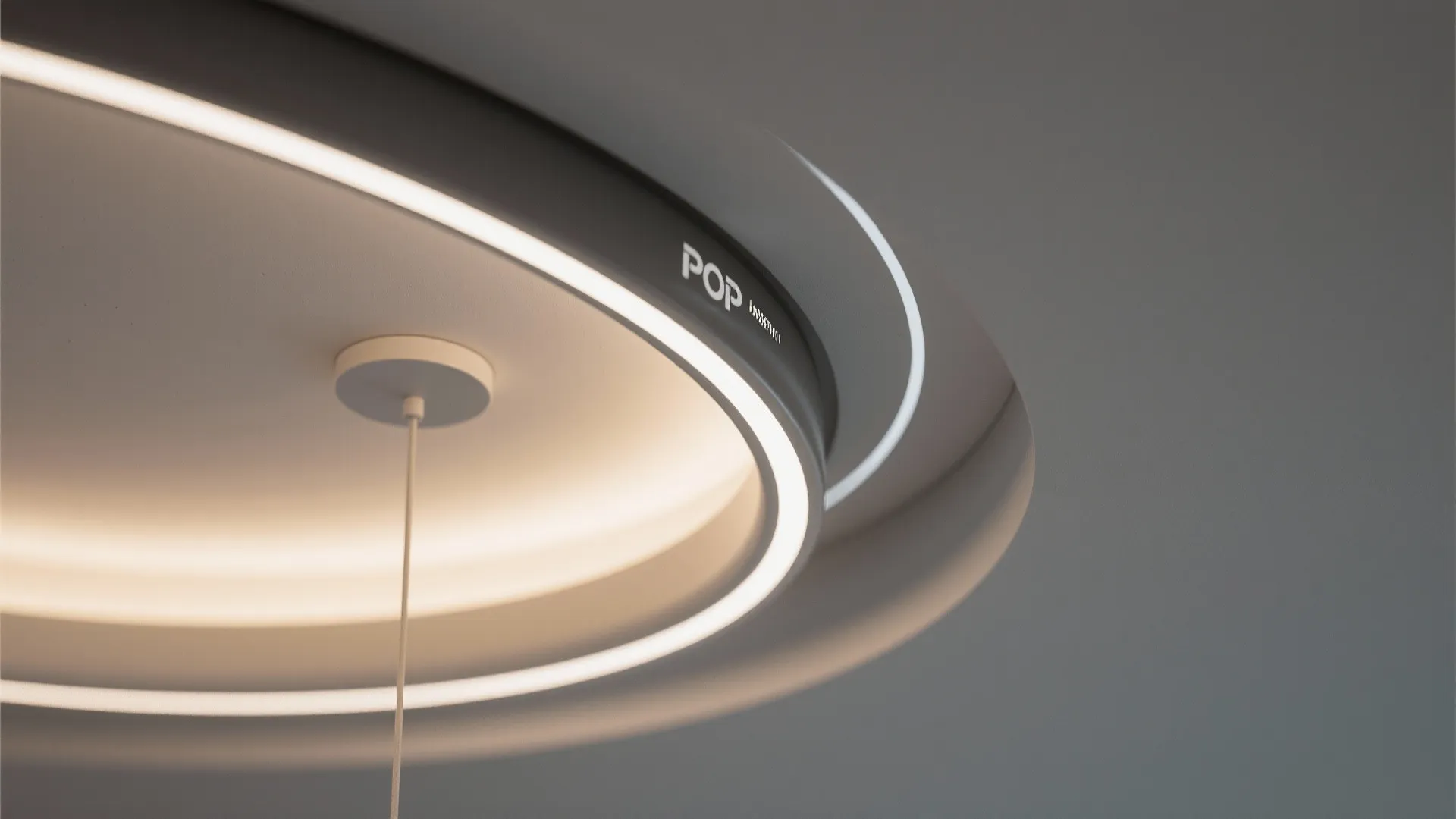 Modern circular ceiling light with glowing led rings and a hanging wire in minimal room