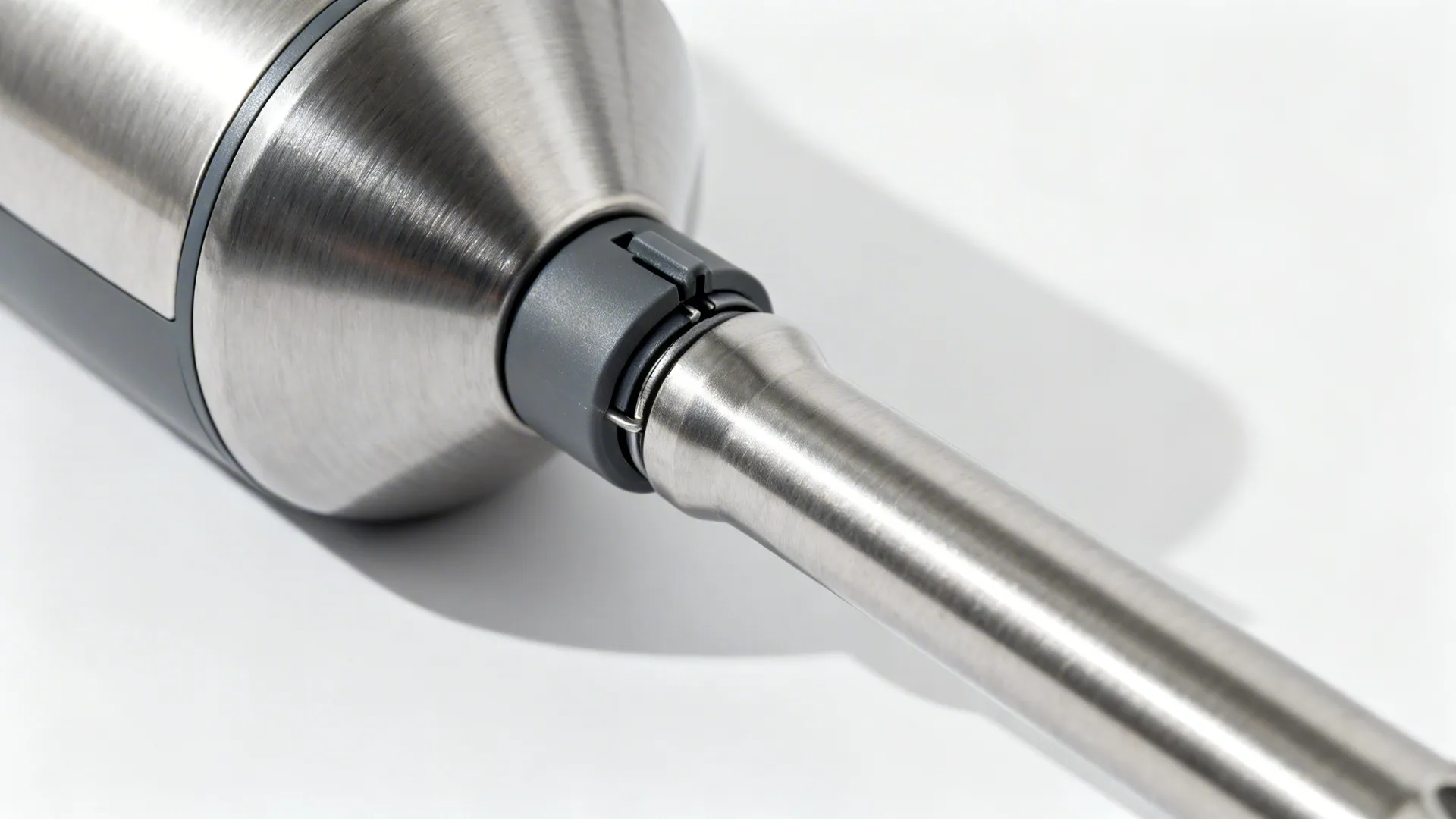 Close up view of stainless steel hand blender connection part on a plain white background