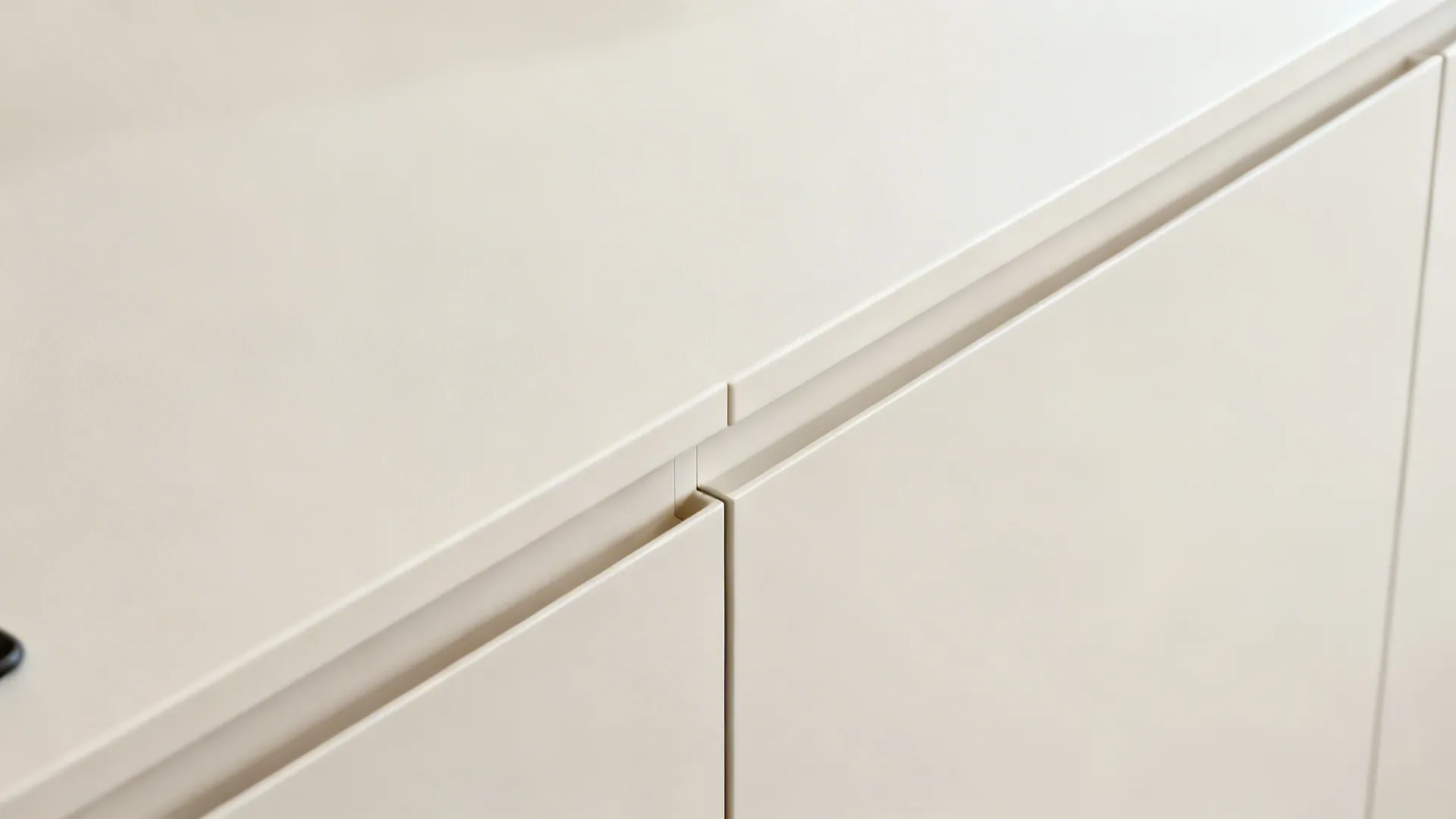 Macro detail of a concealed pull channel on a semi-matte handleless cabinet door.