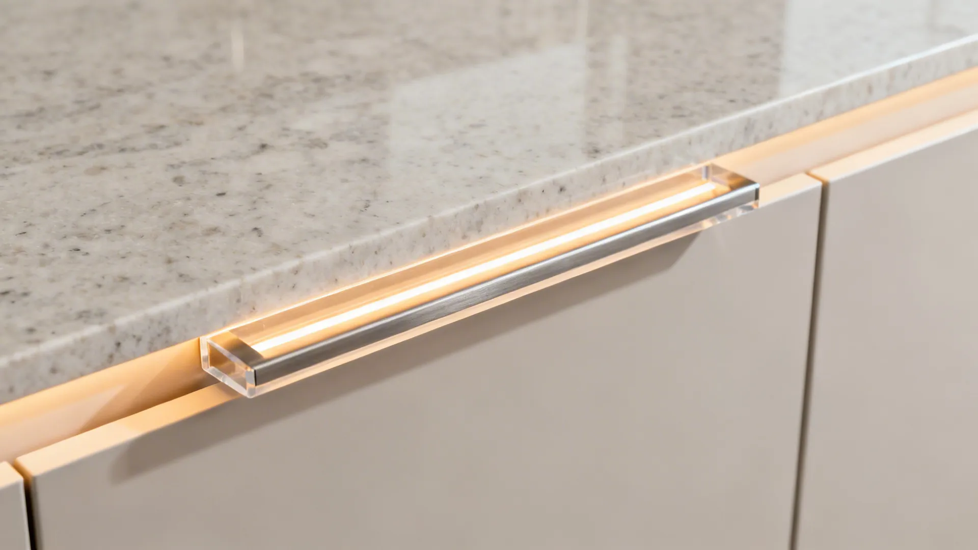 Macro of J-pull acrylic cabinet edge lit by warm LED over quartz top.