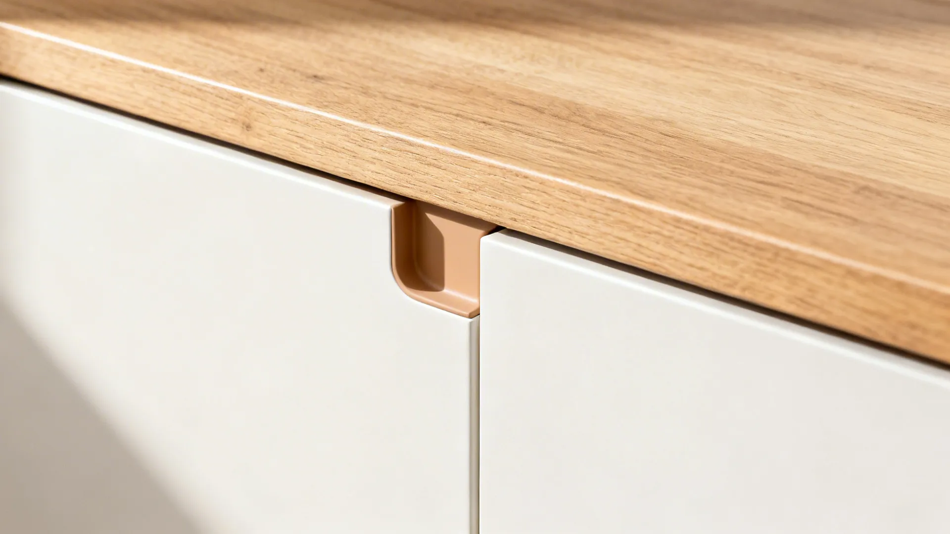 Macro detail of a handleless cabinet pull with precise reveal and warm white finish beside oak.