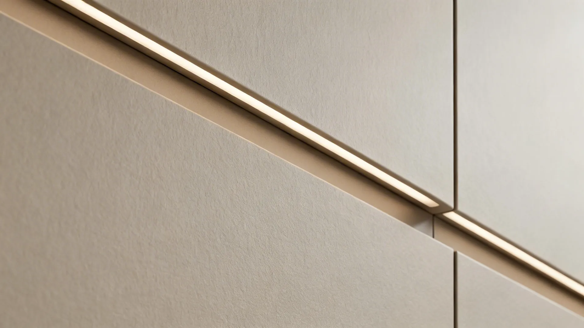 Macro detail of a matte greige handleless cabinet finger-rail with subtle LED glow.