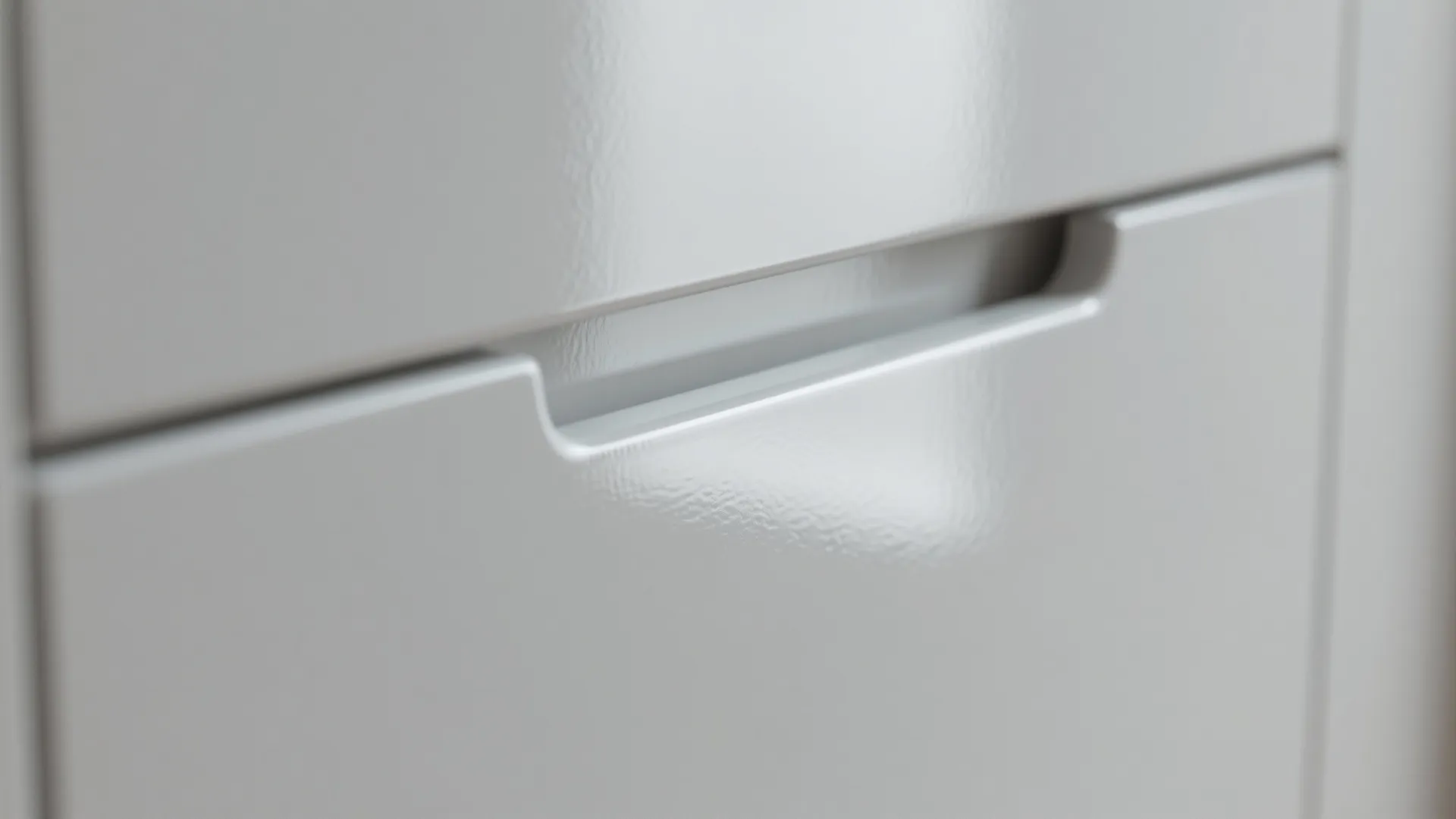 Close-up of handleless glossy white cabinet with recessed rail finger pull
