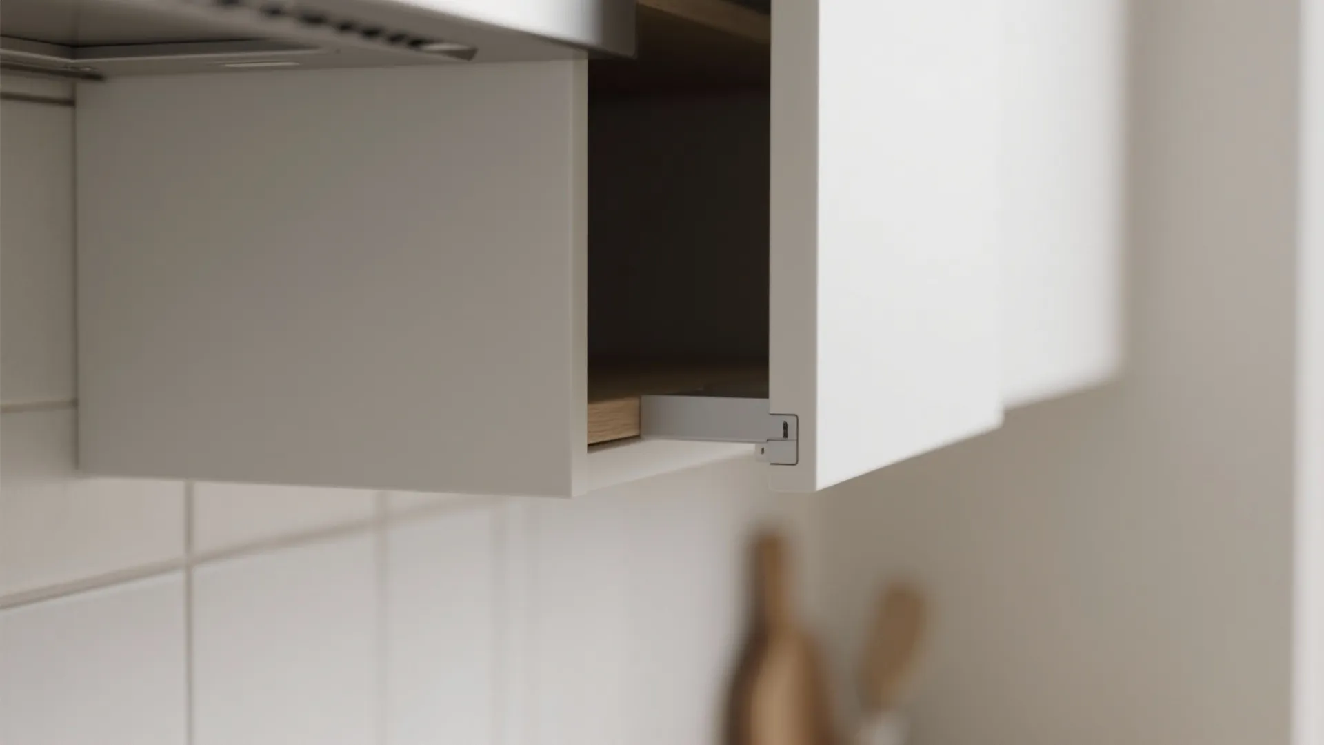 Close up of a white handleless cabinet door opening with a small grey mechanical hinge part