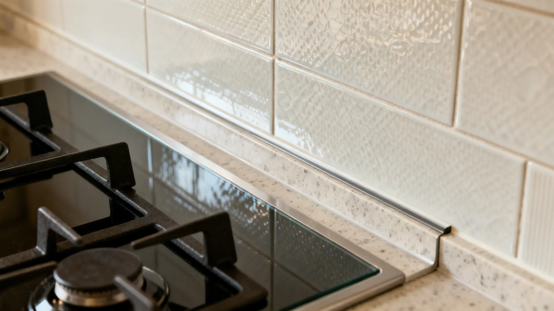 Macro of heat-resistant backsplash and slim hood details near a southeast hob.