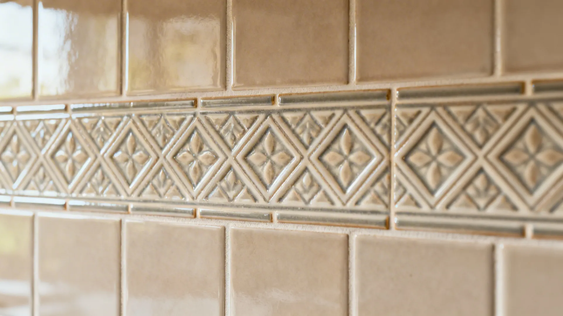 Macro of Chettinad-style patterned porcelain band with tight epoxy grout in a neutral backsplash.