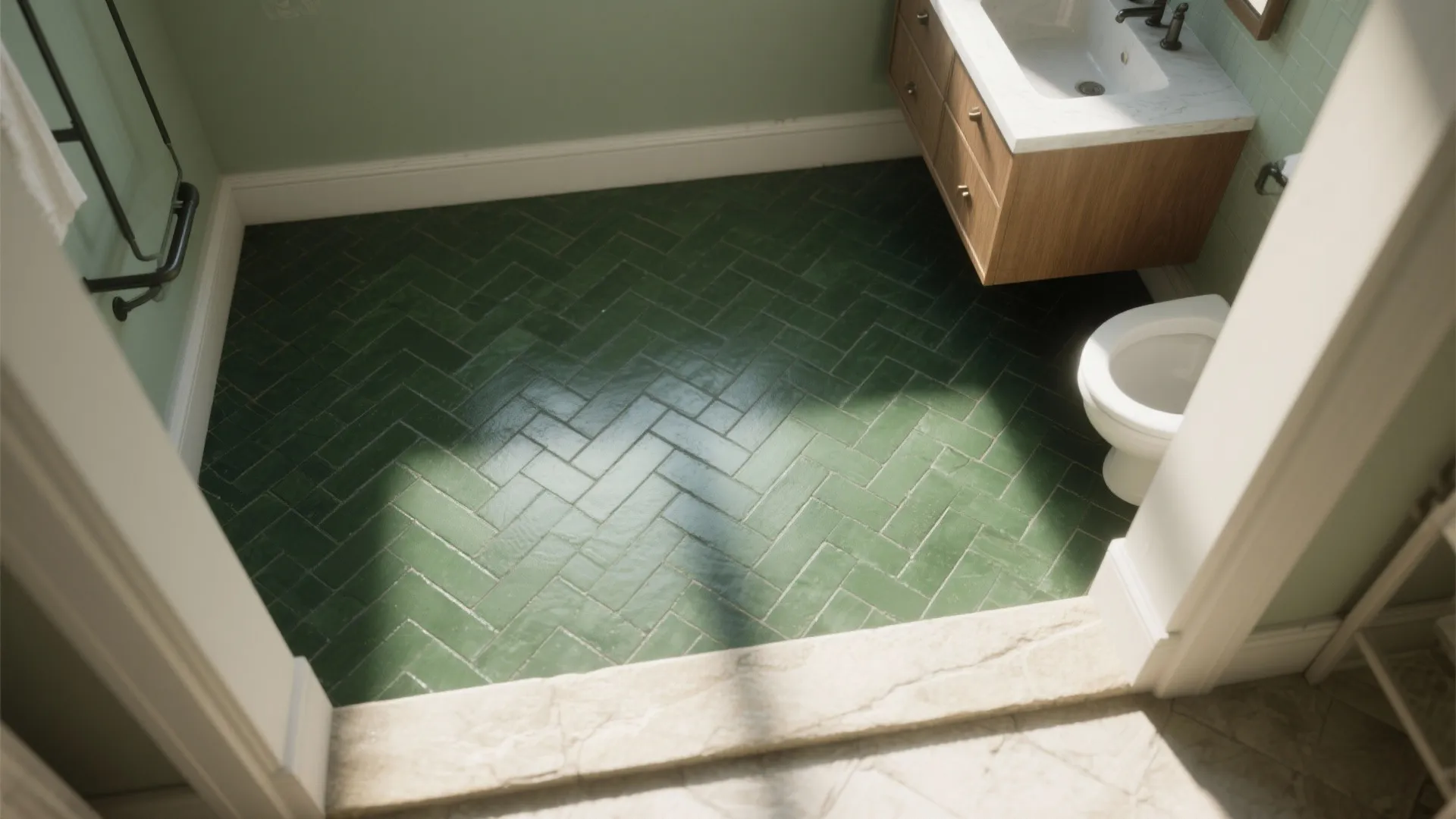 Green herringbone tile floor in a modern bathroom with wood cabinet white sink and toilet