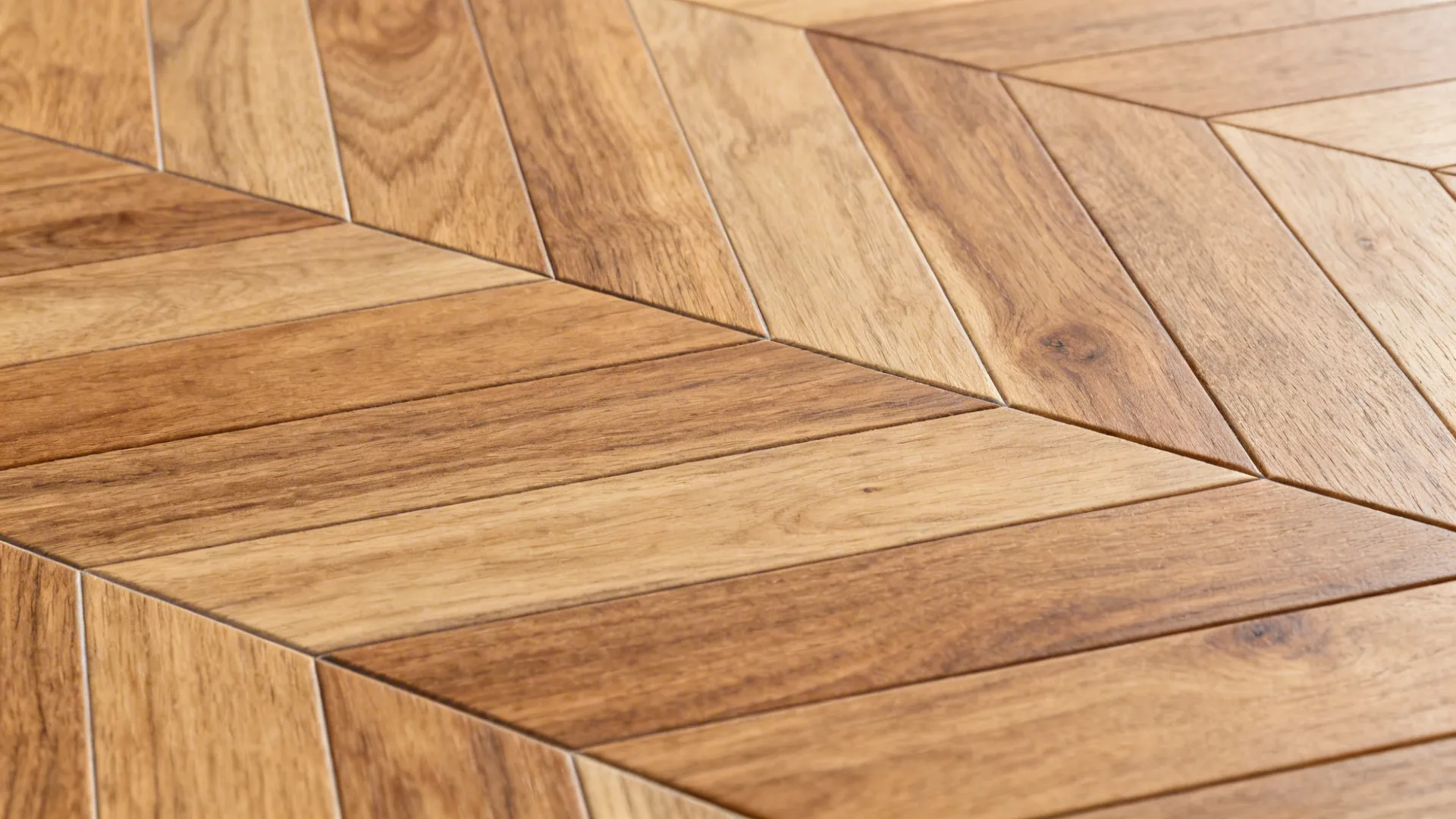 Macro of herringbone wood-look plank with subtle grain and matte finish in a tight joint layout.