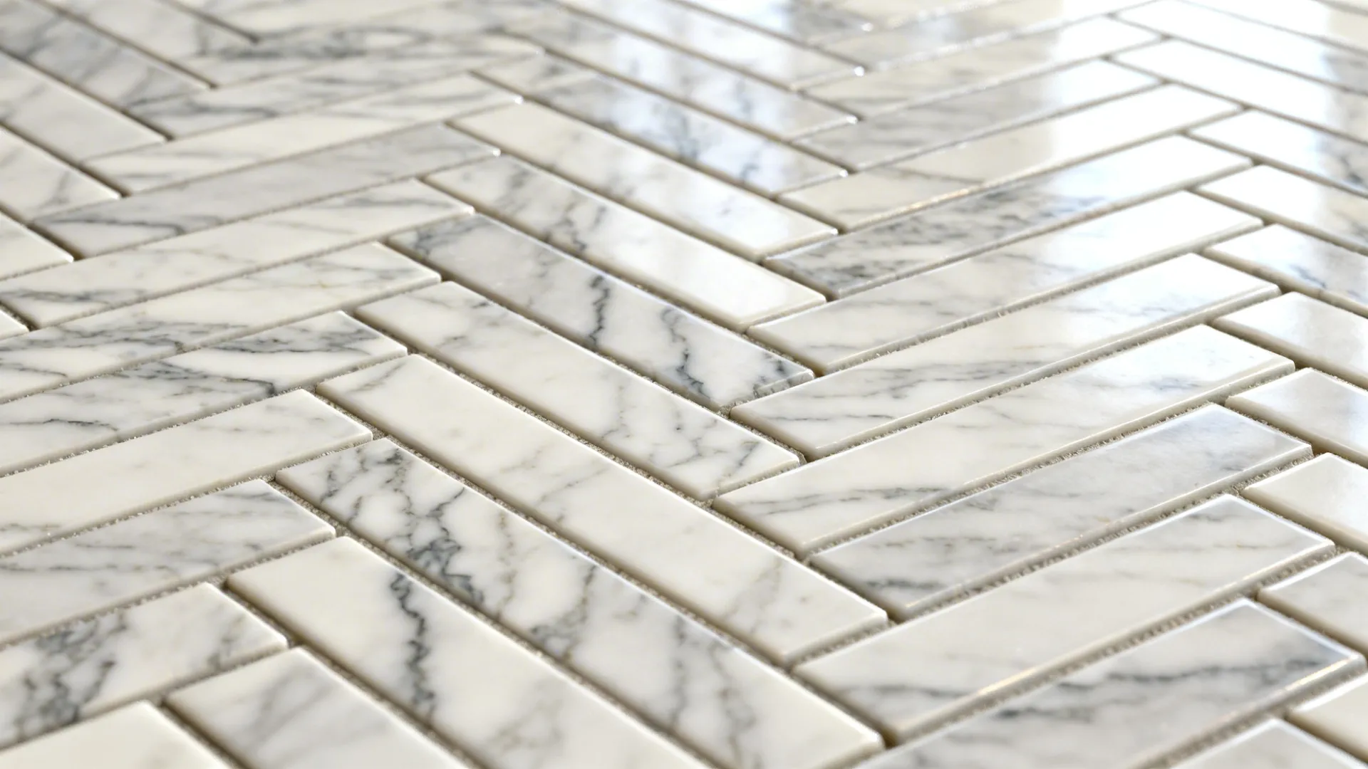 Macro of elongated herringbone marble-look porcelain showing crisp veining and tight grout lines.