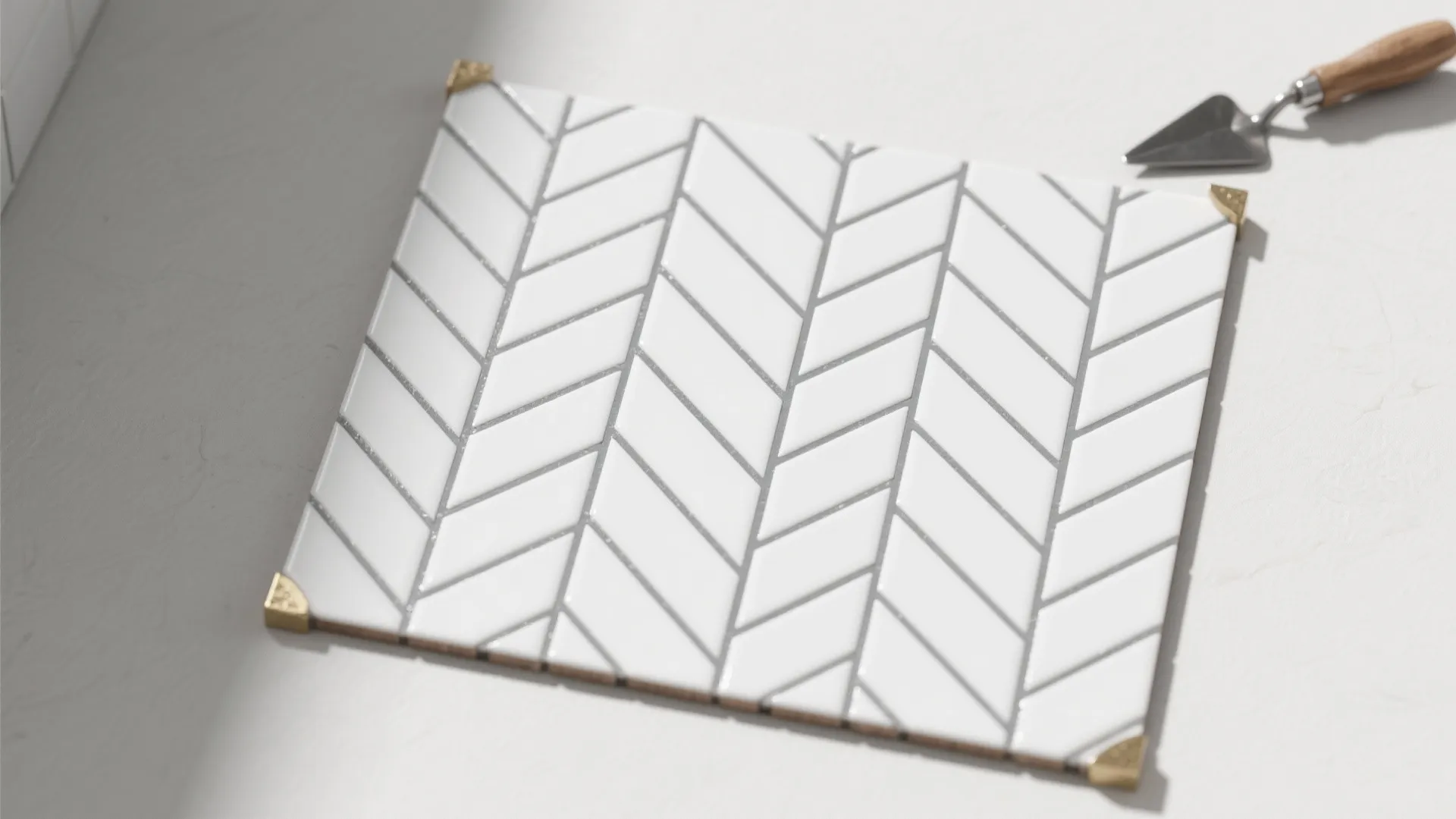 White tile sample with v-shaped pattern and a small hand tool on a white surface