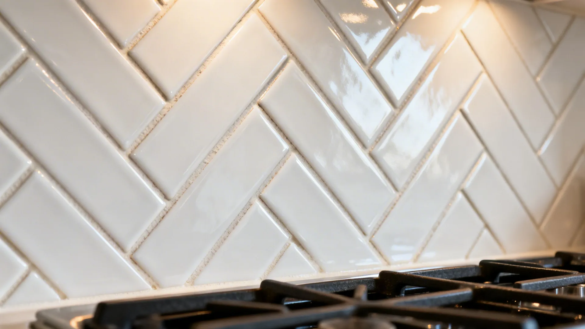 Macro of white herringbone subway tile with warm grout and soft task light