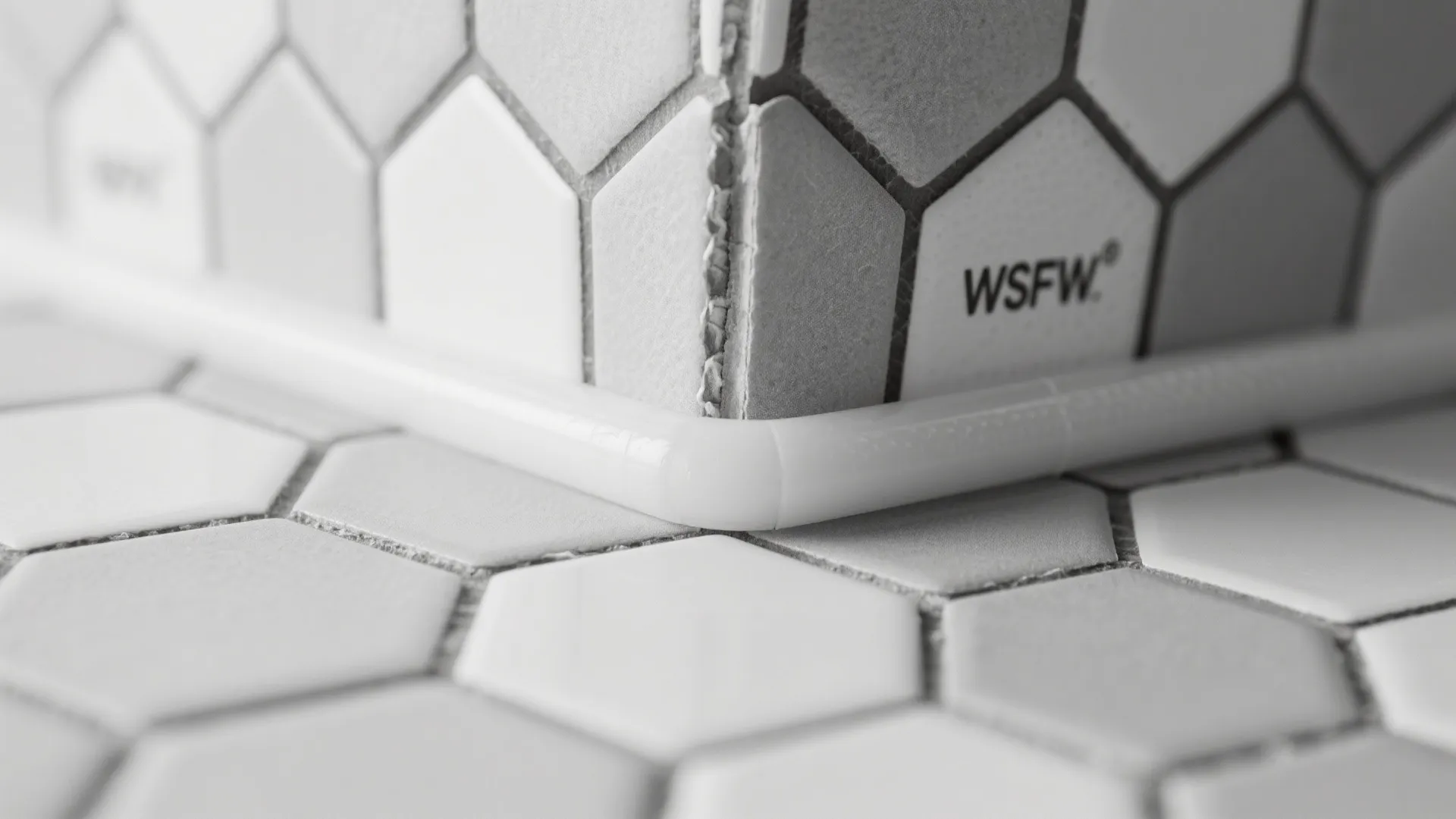 Close up view of white hexagon wall tiles meeting at a corner with white trim piece