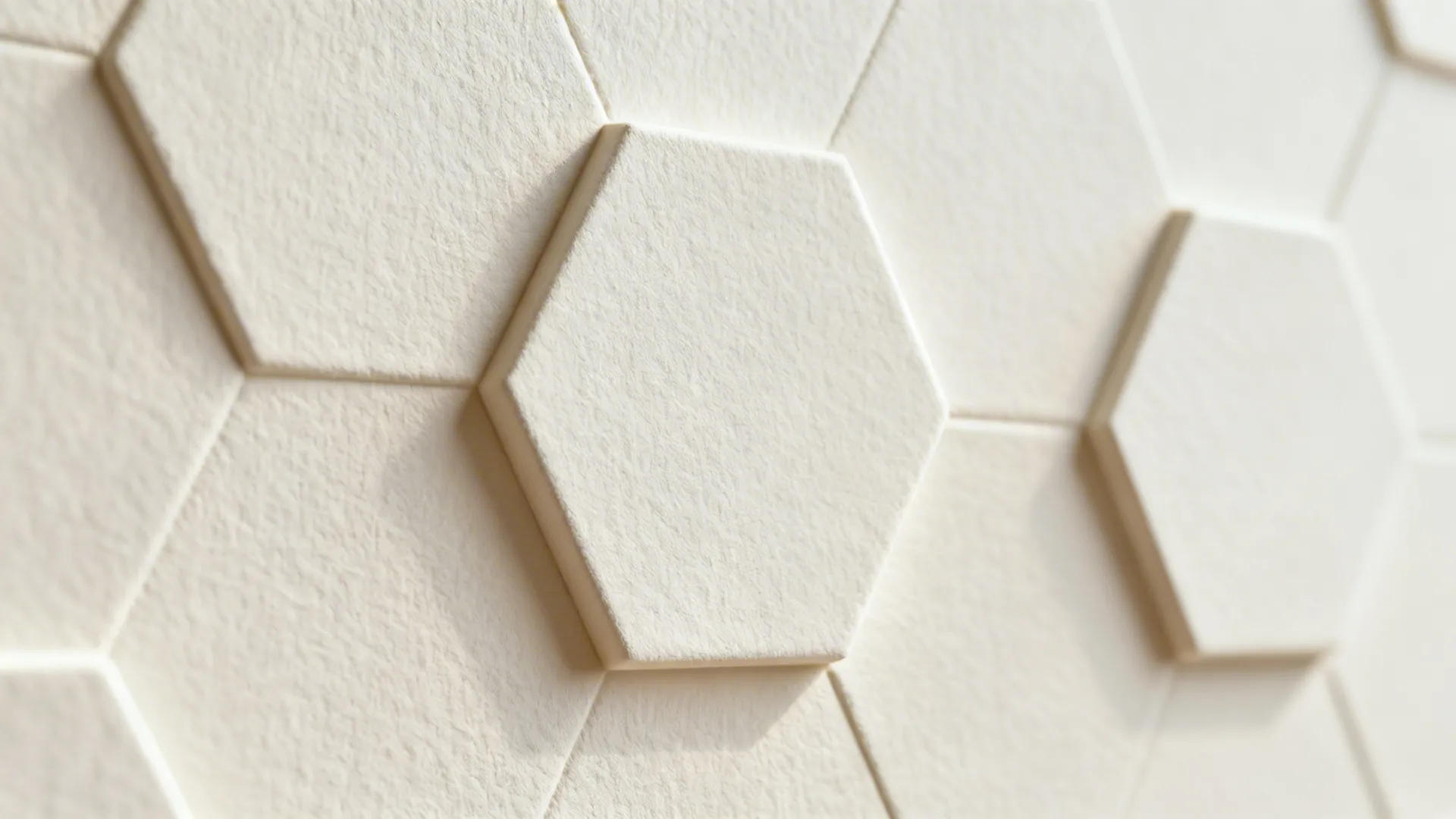 Macro detail of matte off-white hexagonal 3D relief wallpaper with soft shadows.
