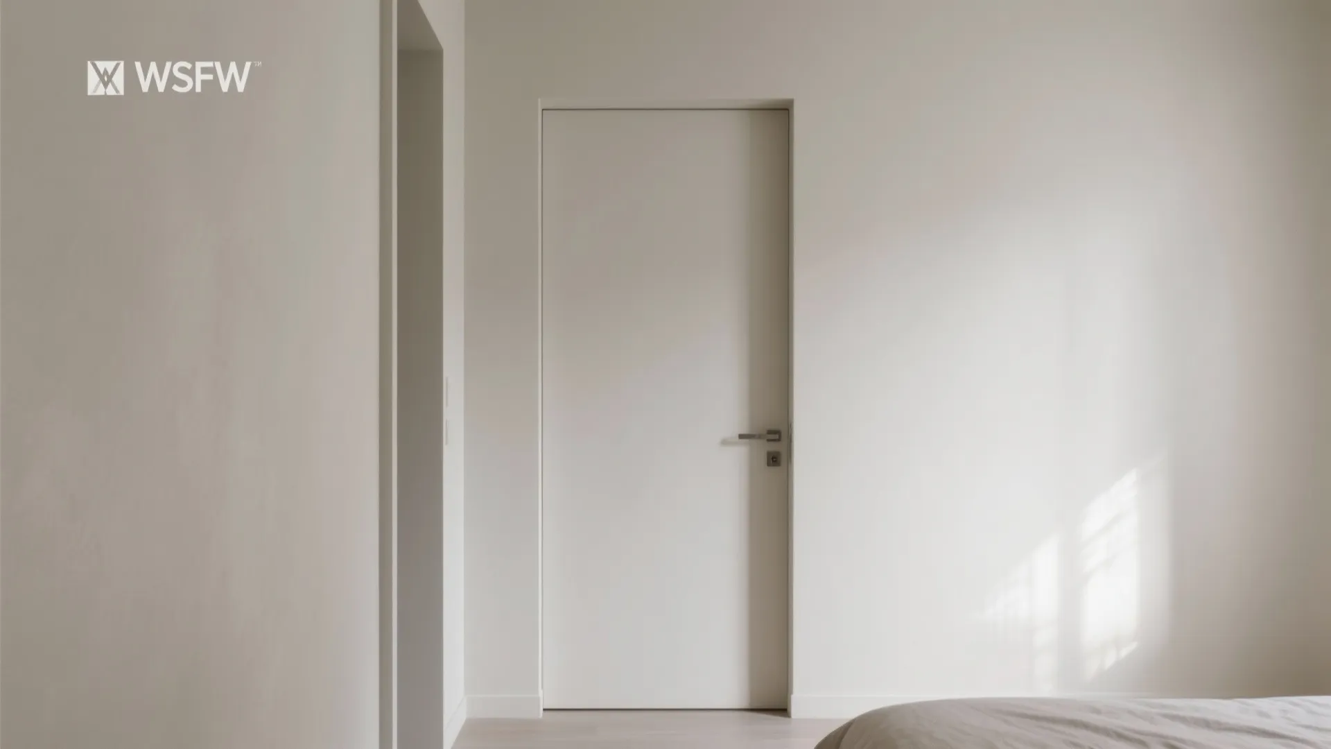 White flush door integrated into plain wall with silver handle in bright modern interior home