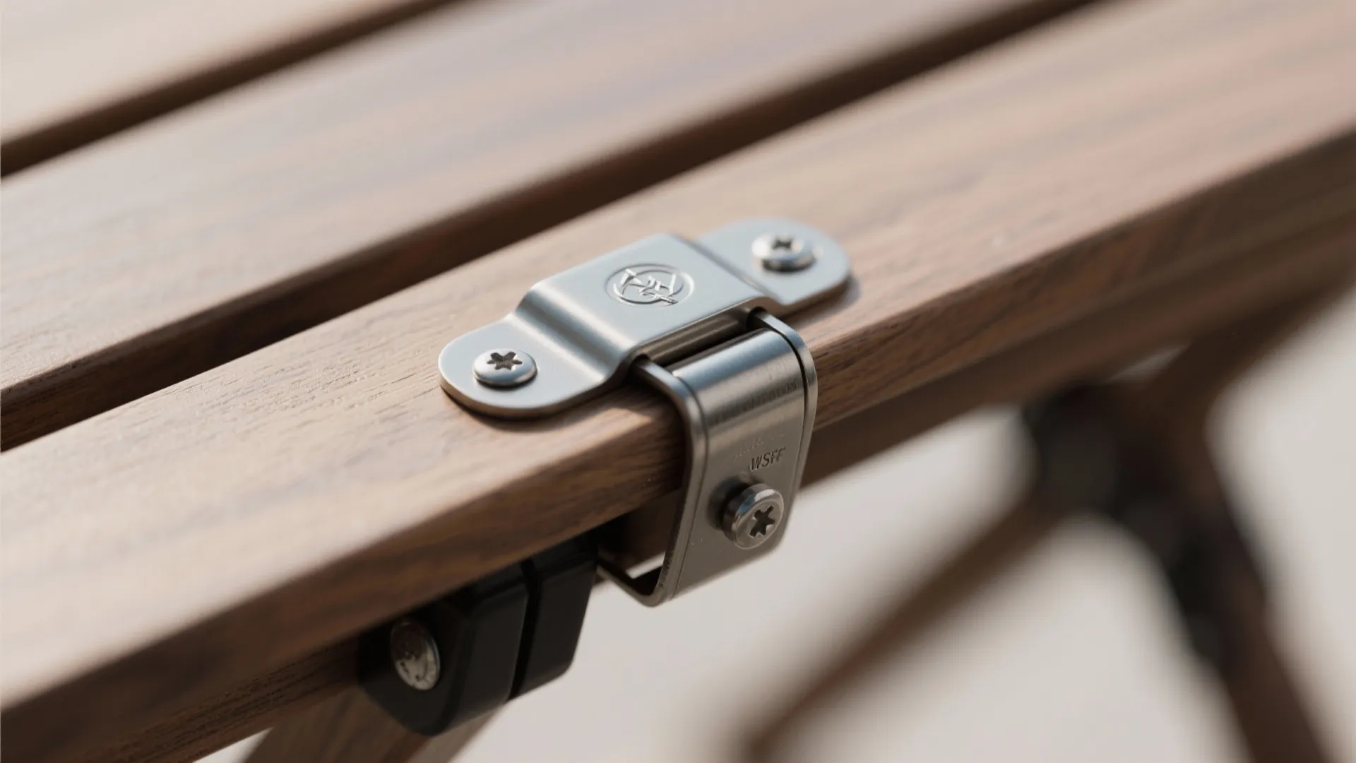 Close up of a metal hinge attached to brown wooden planks with silver screws and bolts