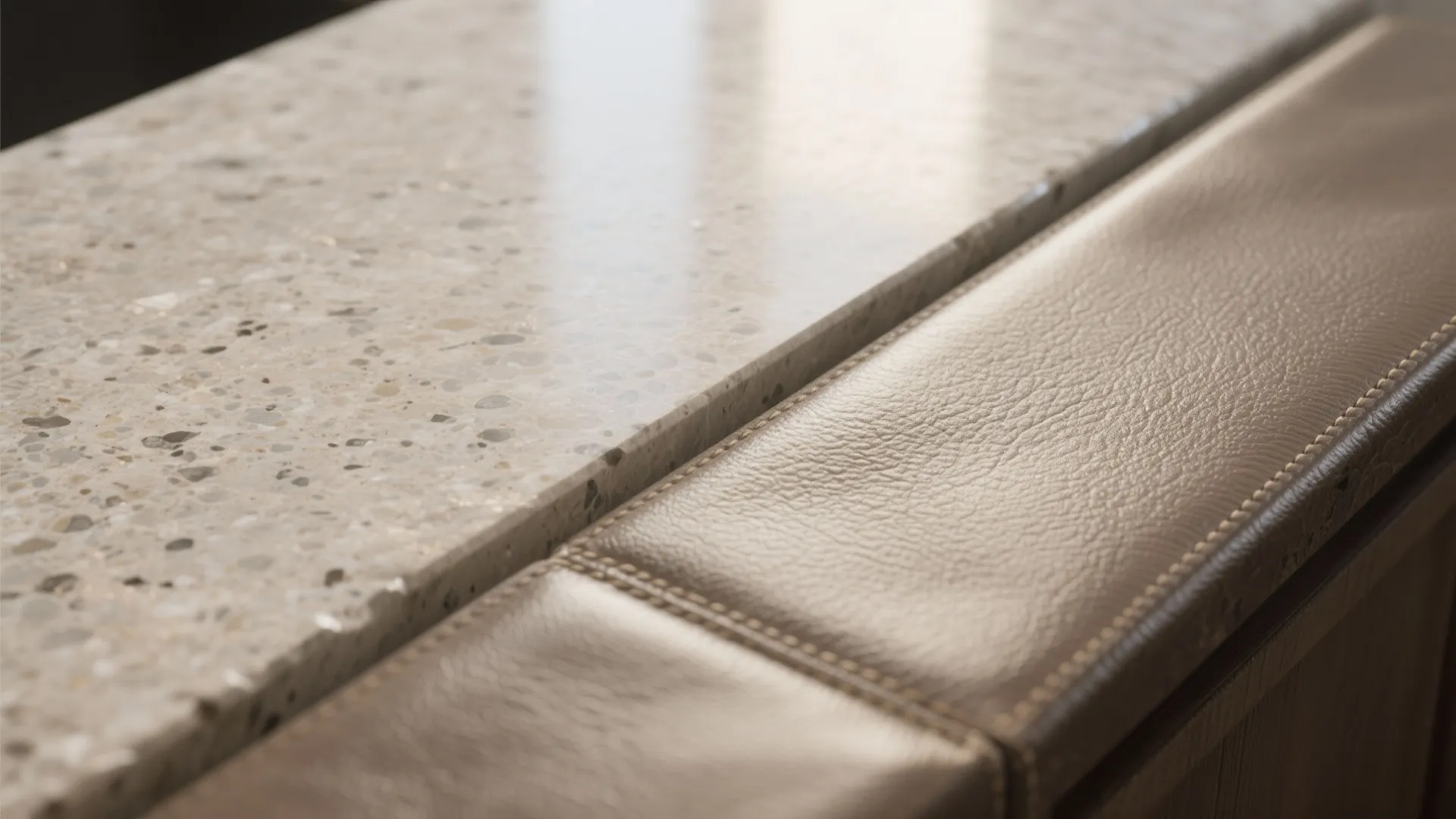 Close-up showing a stone kitchen countertop next to a brown leather surface with detailed stitching