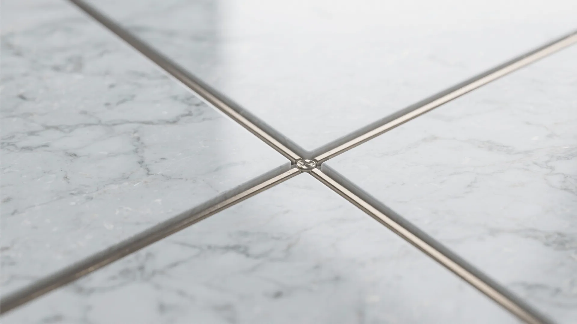 Macro of honed marble with soft satin texture, subtle veins, and clean grout line.