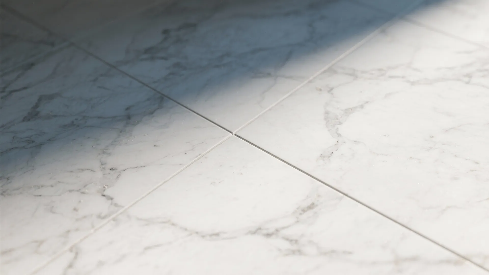 Close up view of clean white marble floor tiles with grey veins and narrow grout