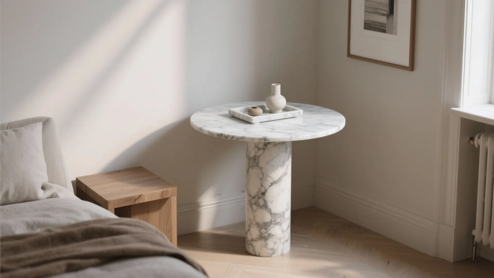 Slim honed marble pedestal and tray styled in a calm small apartment corner.