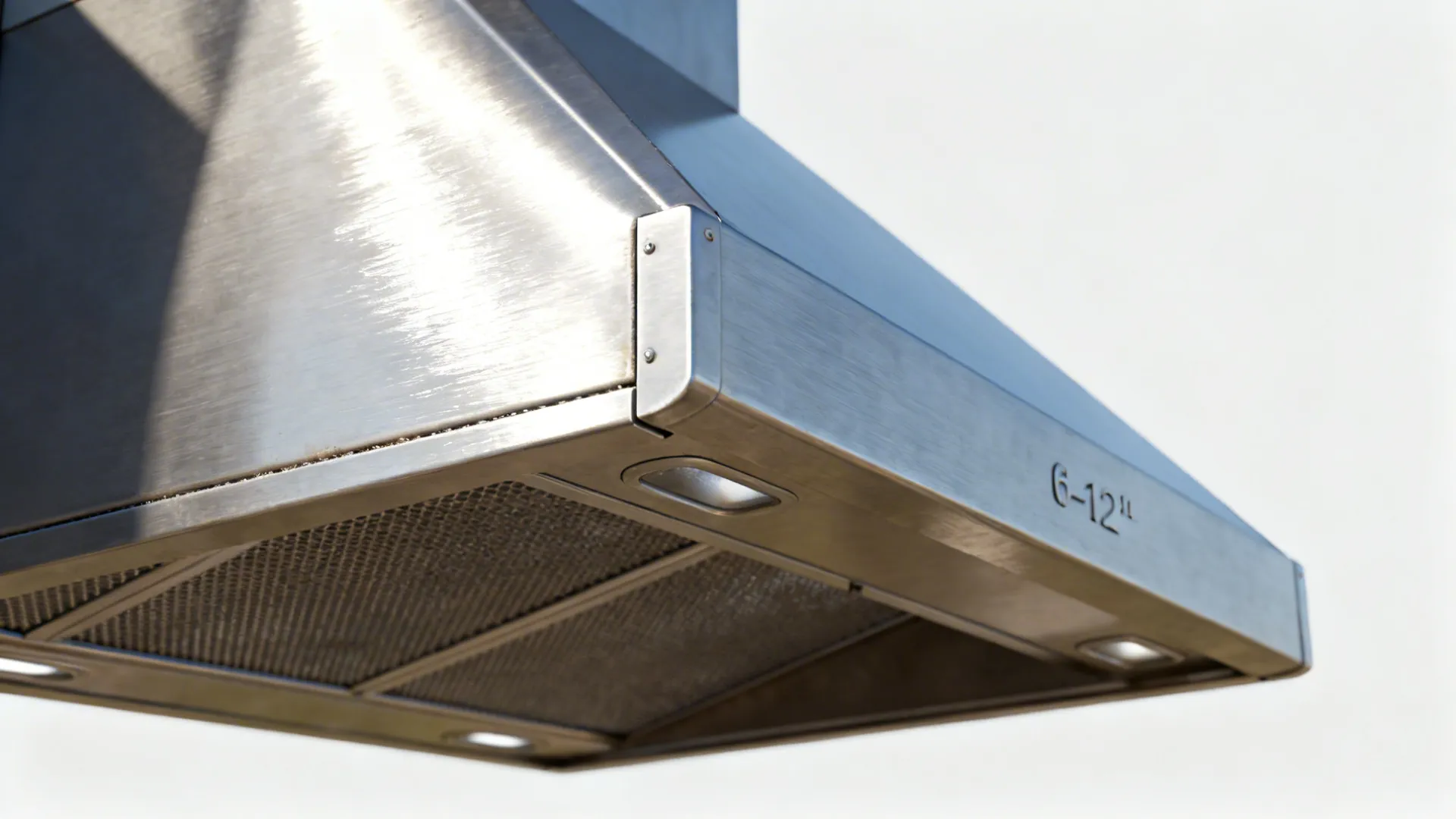 Macro view of stainless hood overhang, side panel, and baffle filters with precise seams.