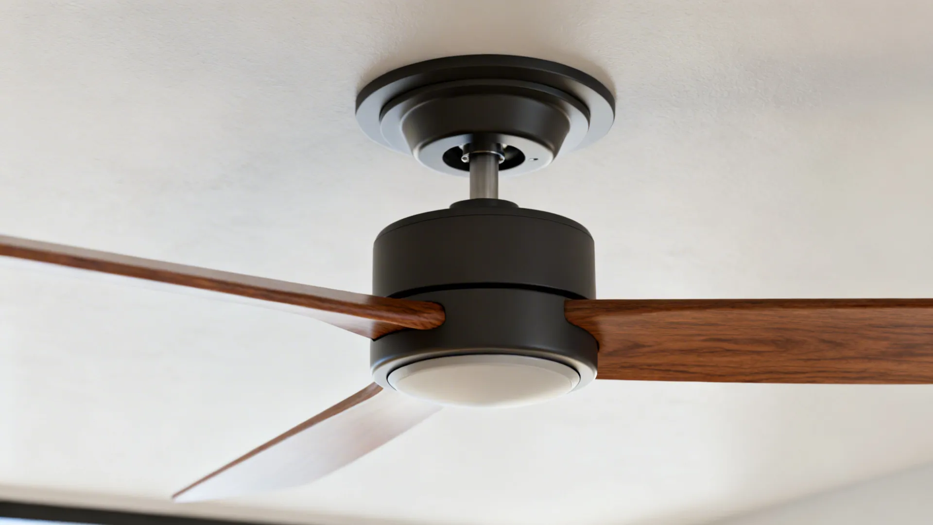 Close-up of a low-profile hugger fan's slim motor housing and blade root against a ceiling