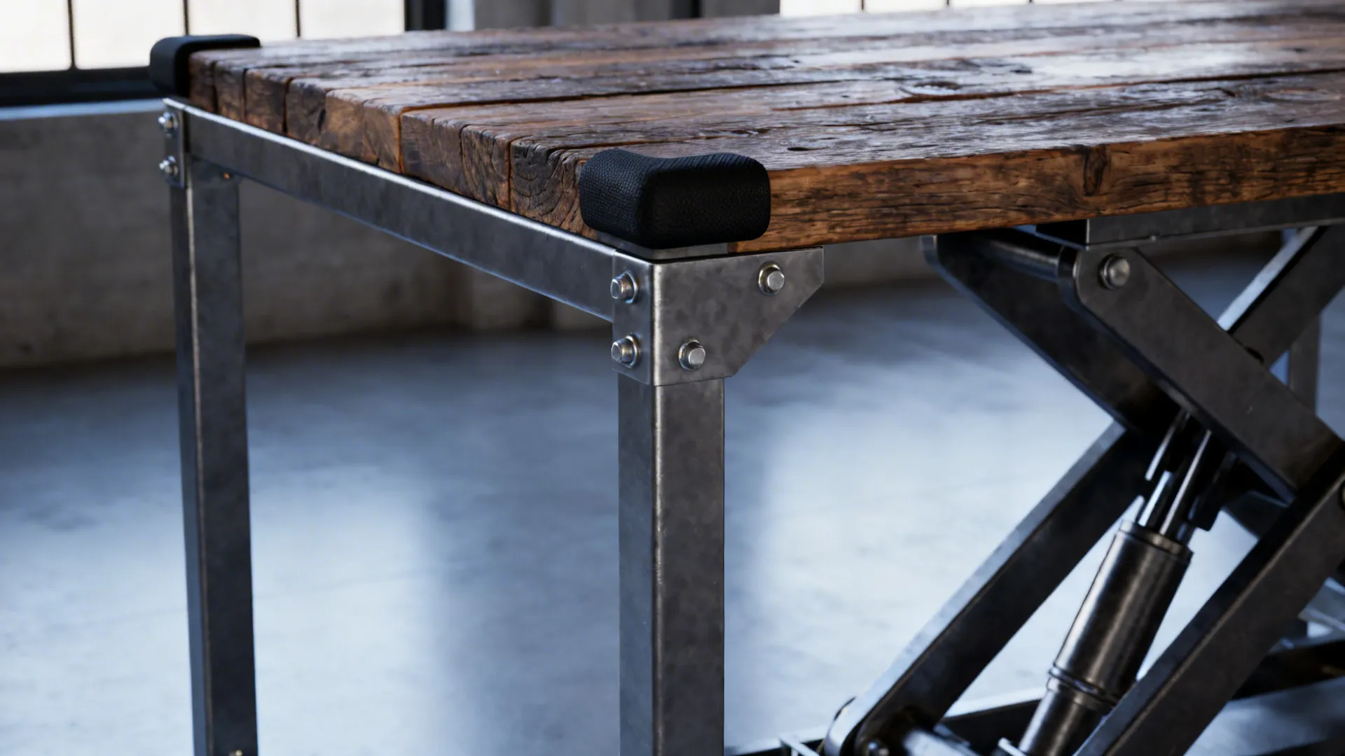 Industrial-style lift table corner showing metal frame, rubber bumpers and reclaimed wood top