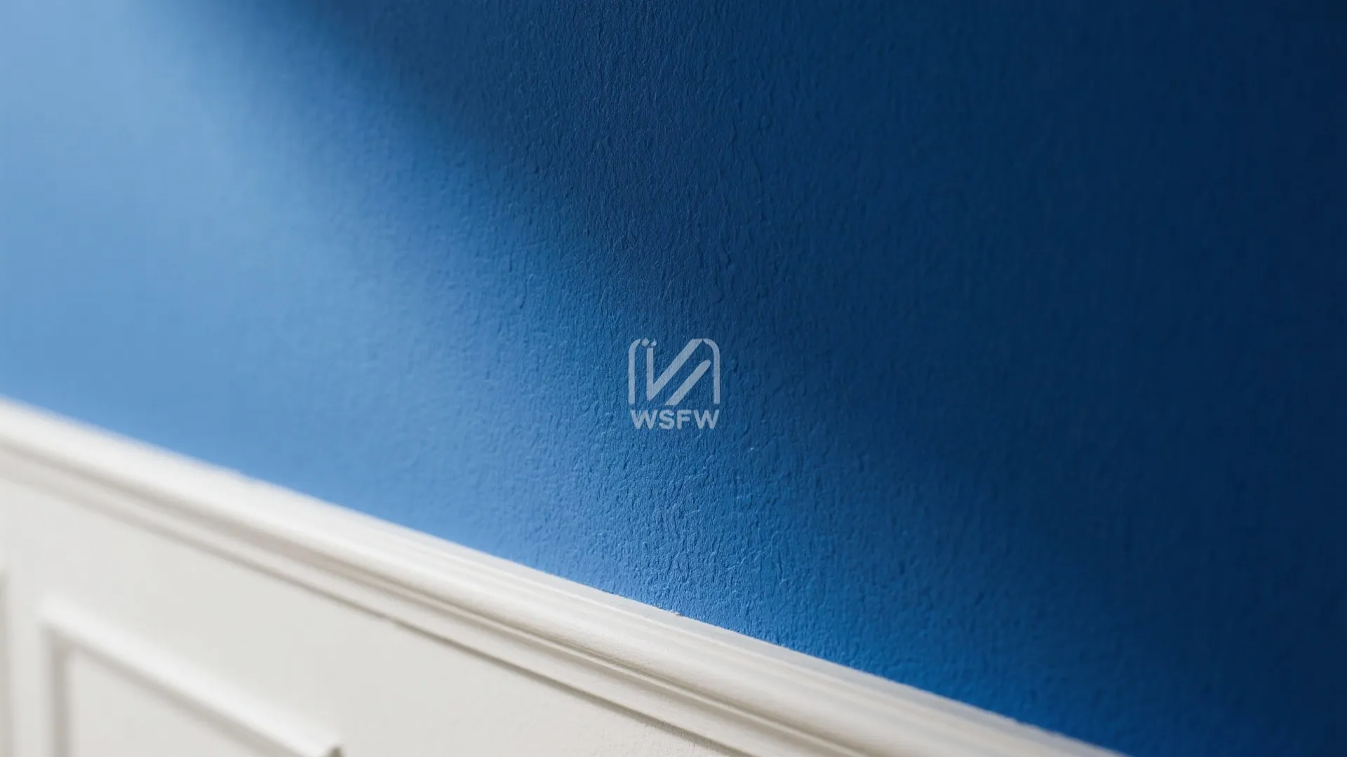 Macro of matte inky blue wall meeting pale off-white trim with a crisp paint line.