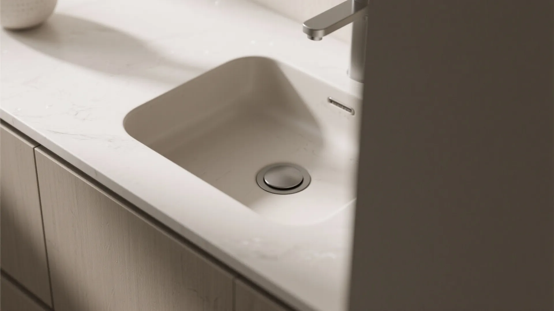 Modern white bathroom sink with silver tap integrated into a white marble stone counter top surface