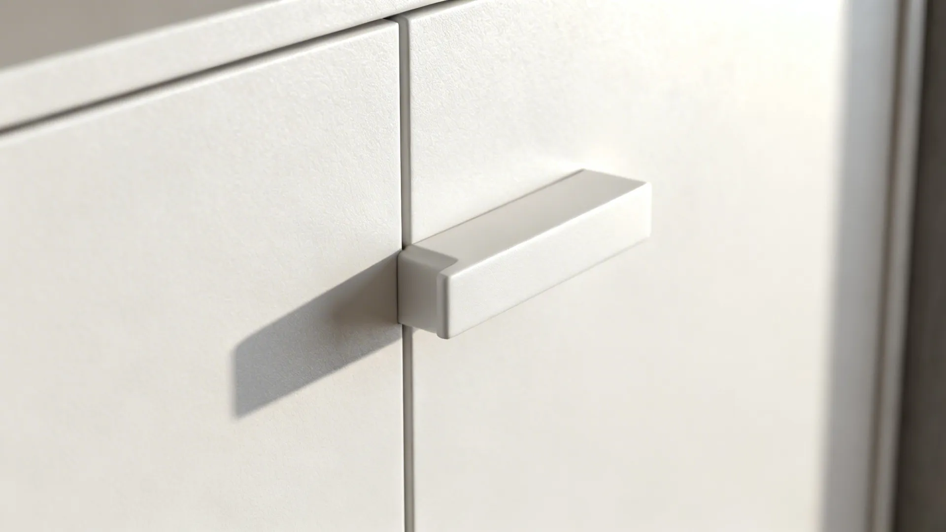 Macro of integrated cabinet pull on a matte white flat-panel kitchen door.