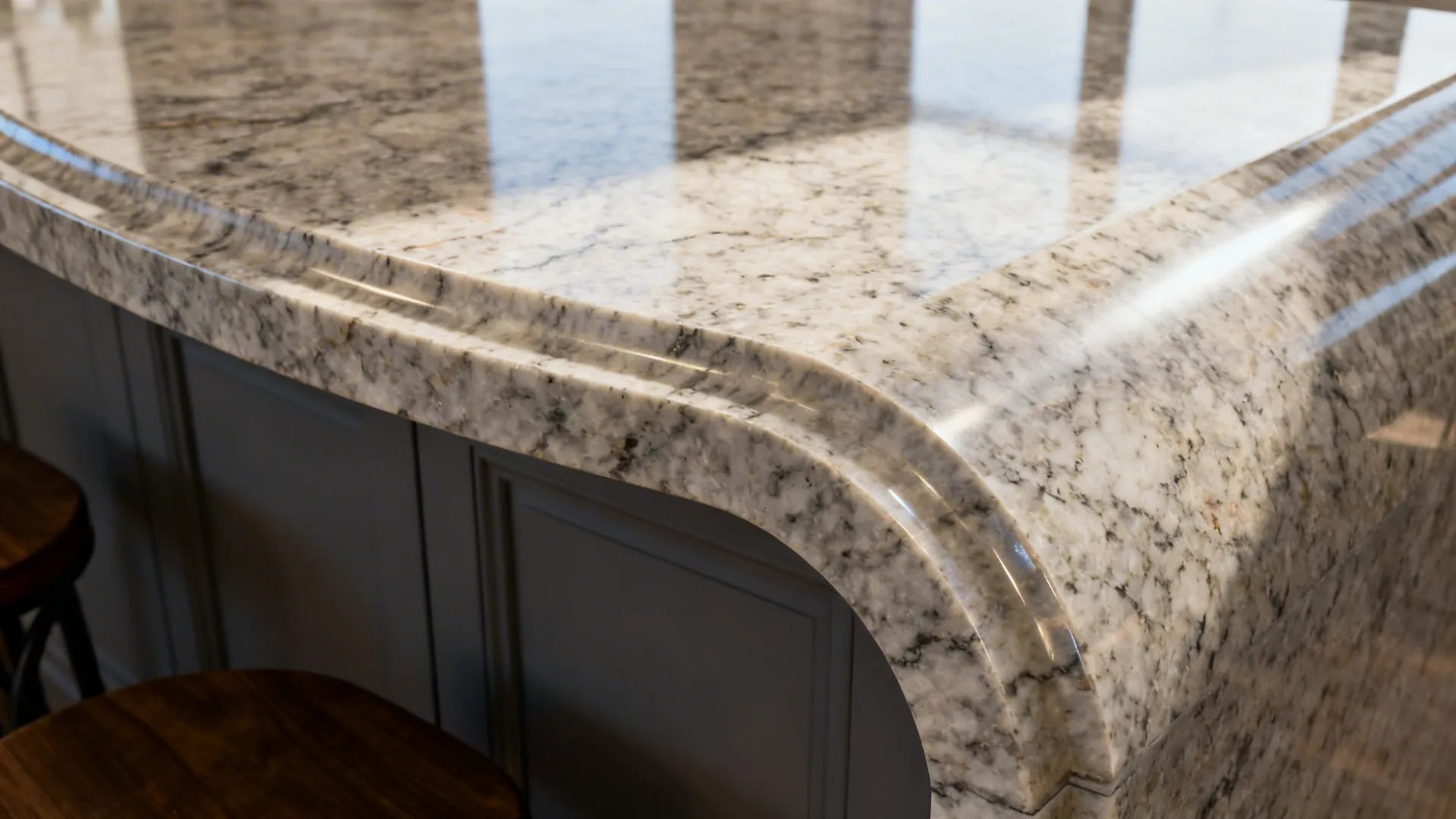 Close-up of a granite island’s curved end flowing into a waterfall return with seamless veining.