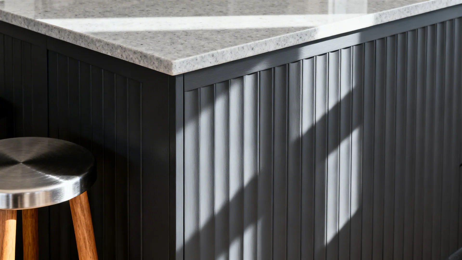 Macro of fluted charcoal island panel with light stone top and brushed metal detail.