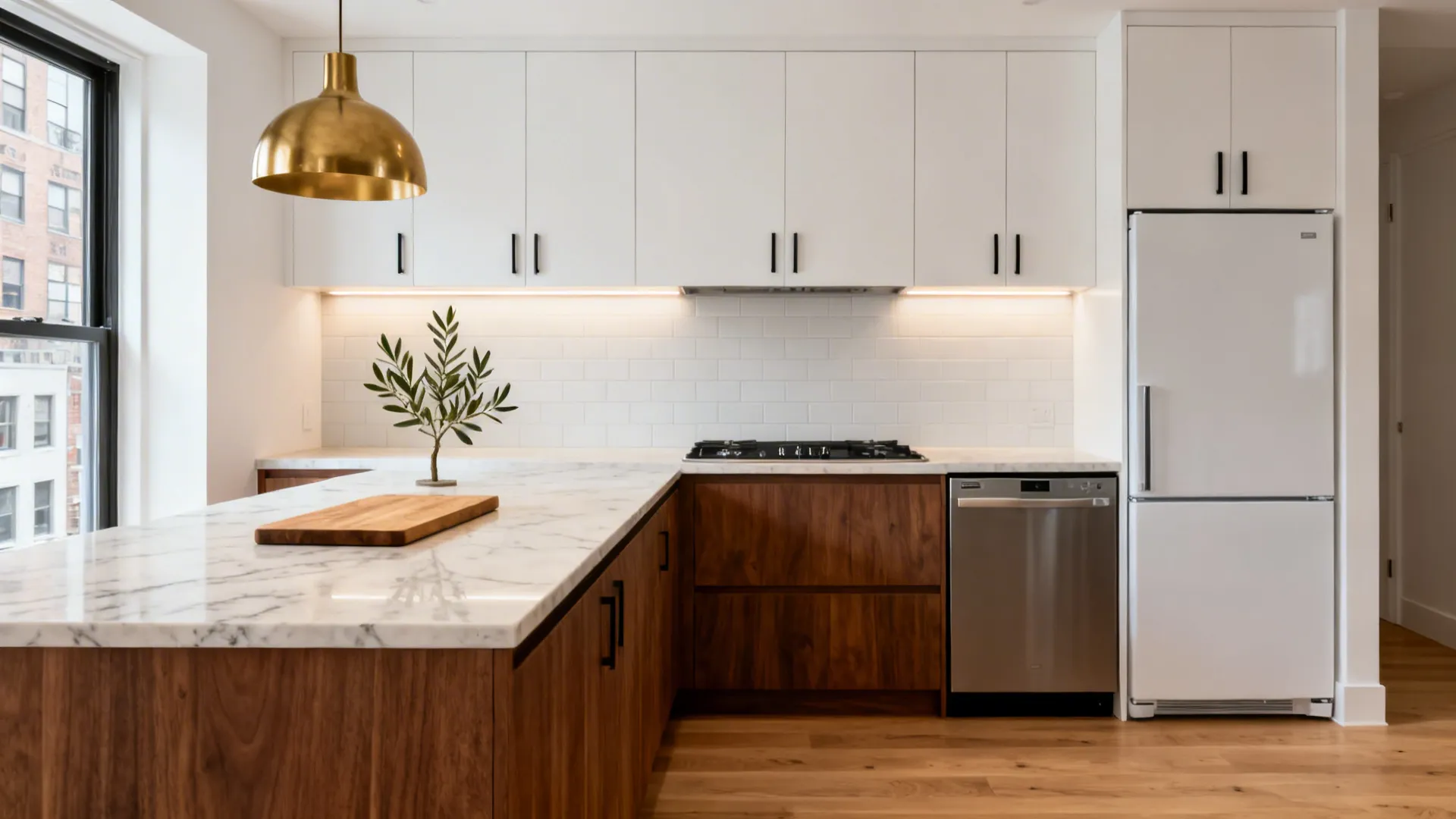Small modern kitchen with white upper cabinets wood lower cabinets marble island and gold ceiling light
