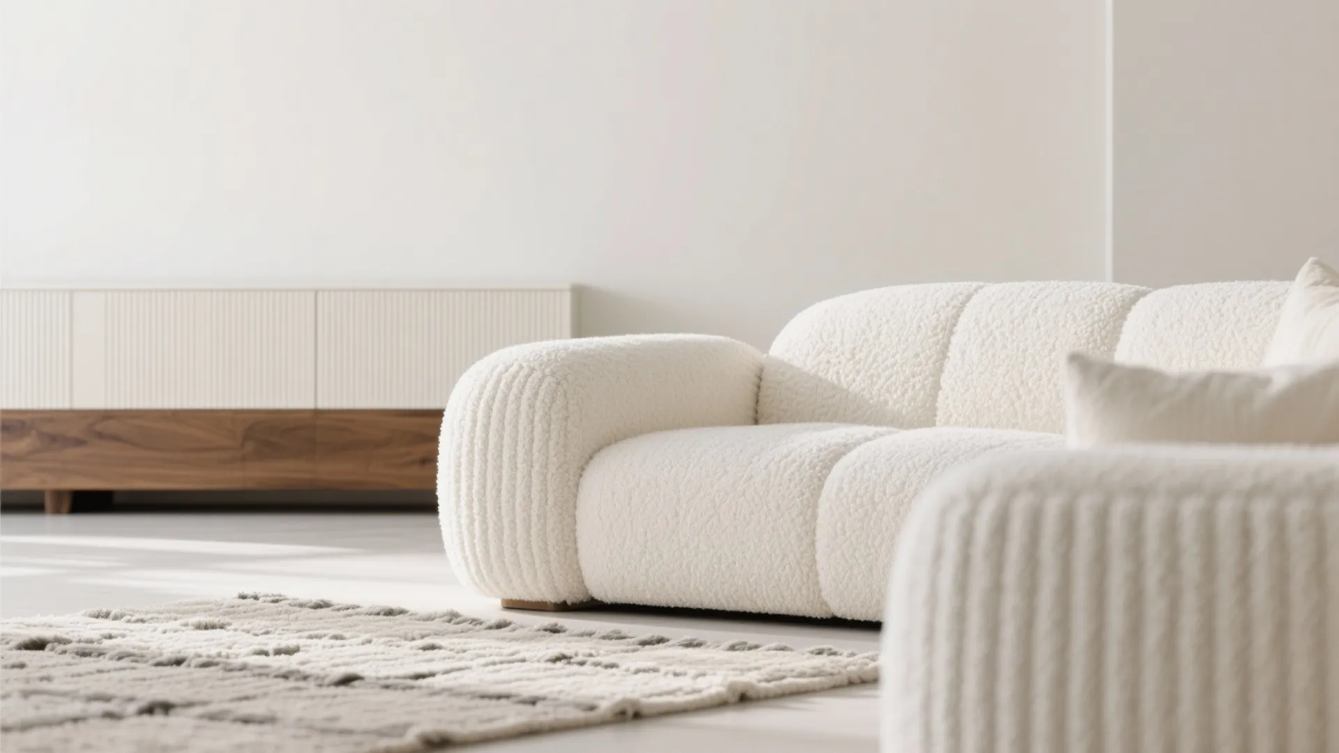 White textured sofa with soft cushions near a grey rug and a wooden storage cabinet