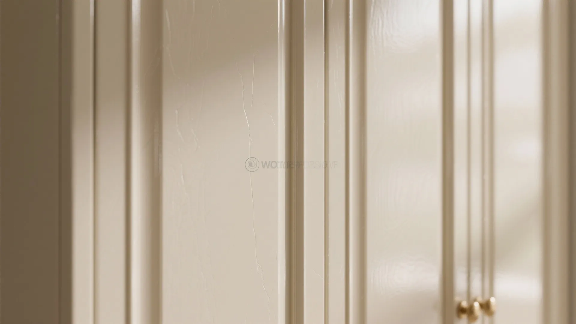Close up of glossy ivory cabinet doors showing smooth finish texture with small gold door knobs