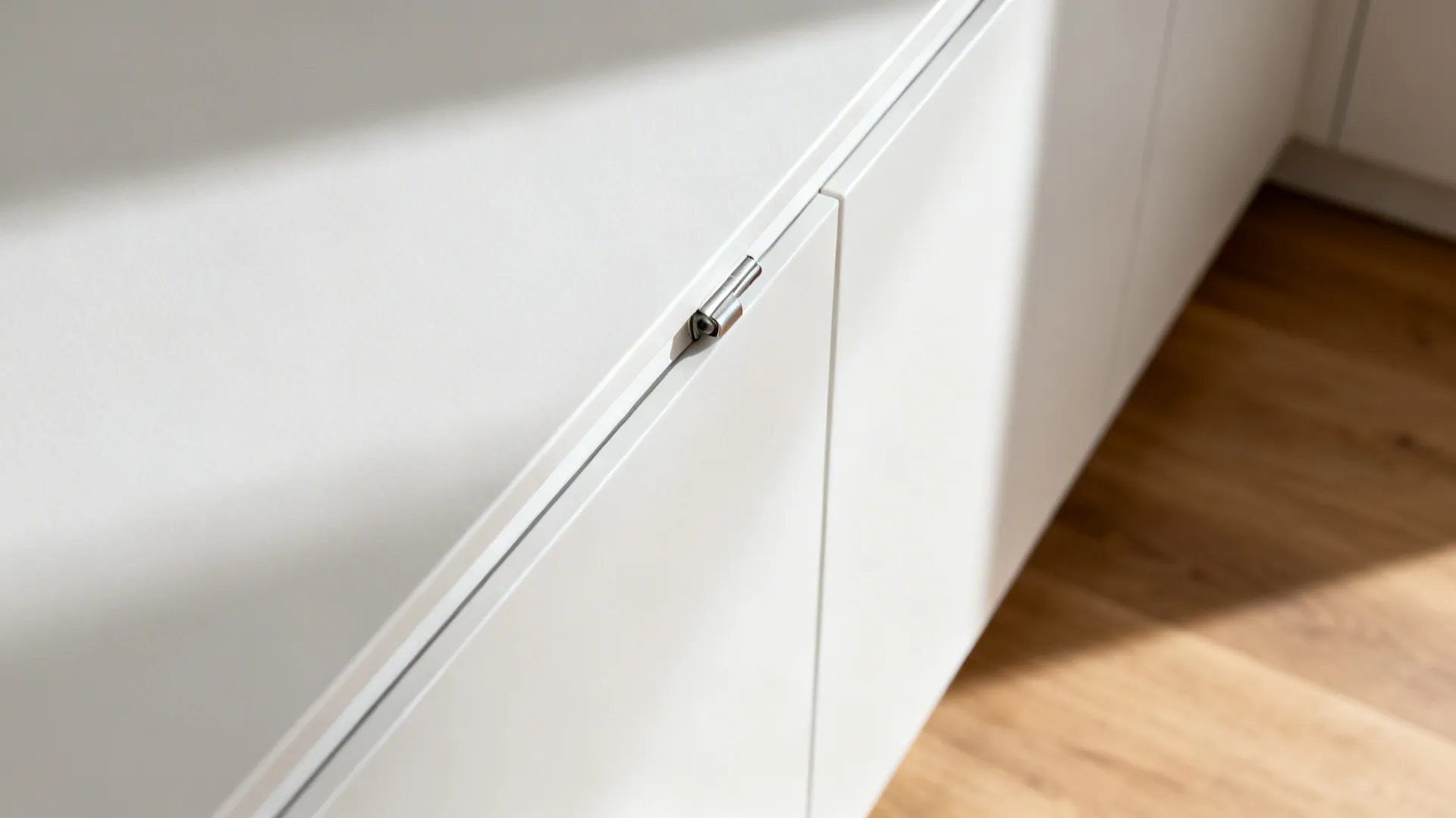 Macro view of a J-pull cabinet edge showing precise handleless detail and hinge alignment.