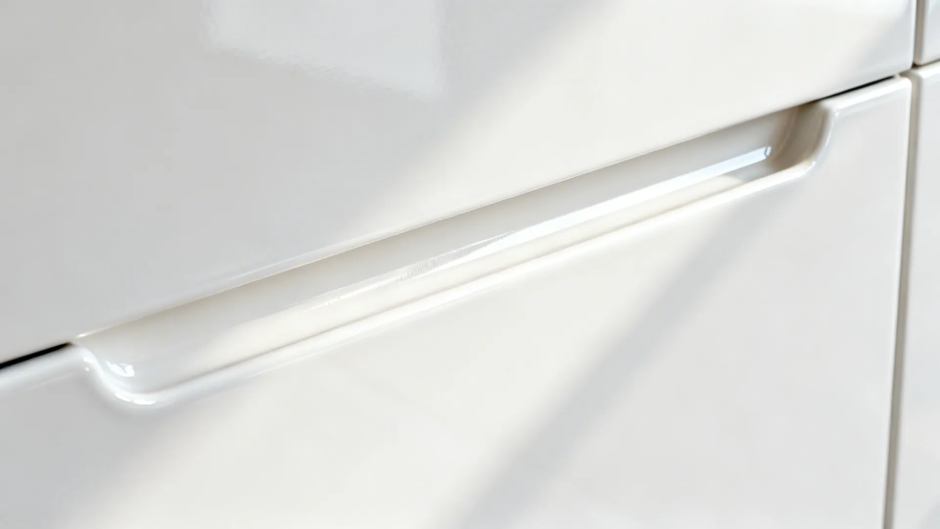 Macro detail of a white gloss cabinet’s J-pull groove with smooth sealed edges.